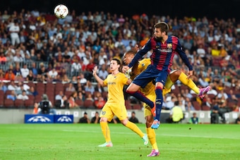 BARCELONA, SPAIN - SEPTEMBER 17: Gerard Pique of FC Barcelona heads the ball towards goal under a challenge by Joao Guilherme of APOEL FC during the UEFA Champions League Group F match between FC Barcelona and APOEL FC at the Camp Nou Stadium on Septembe BARCELONA, SPAIN - SEPTEMBER 17: Gerard Pique of FC Barcelona heads the ball towards goal under a challenge by Joao Guilherme of APOEL FC during the UEFA Champions League Group F match between FC Barcelona and APOEL FC at the Camp Nou Stadium on Septembe