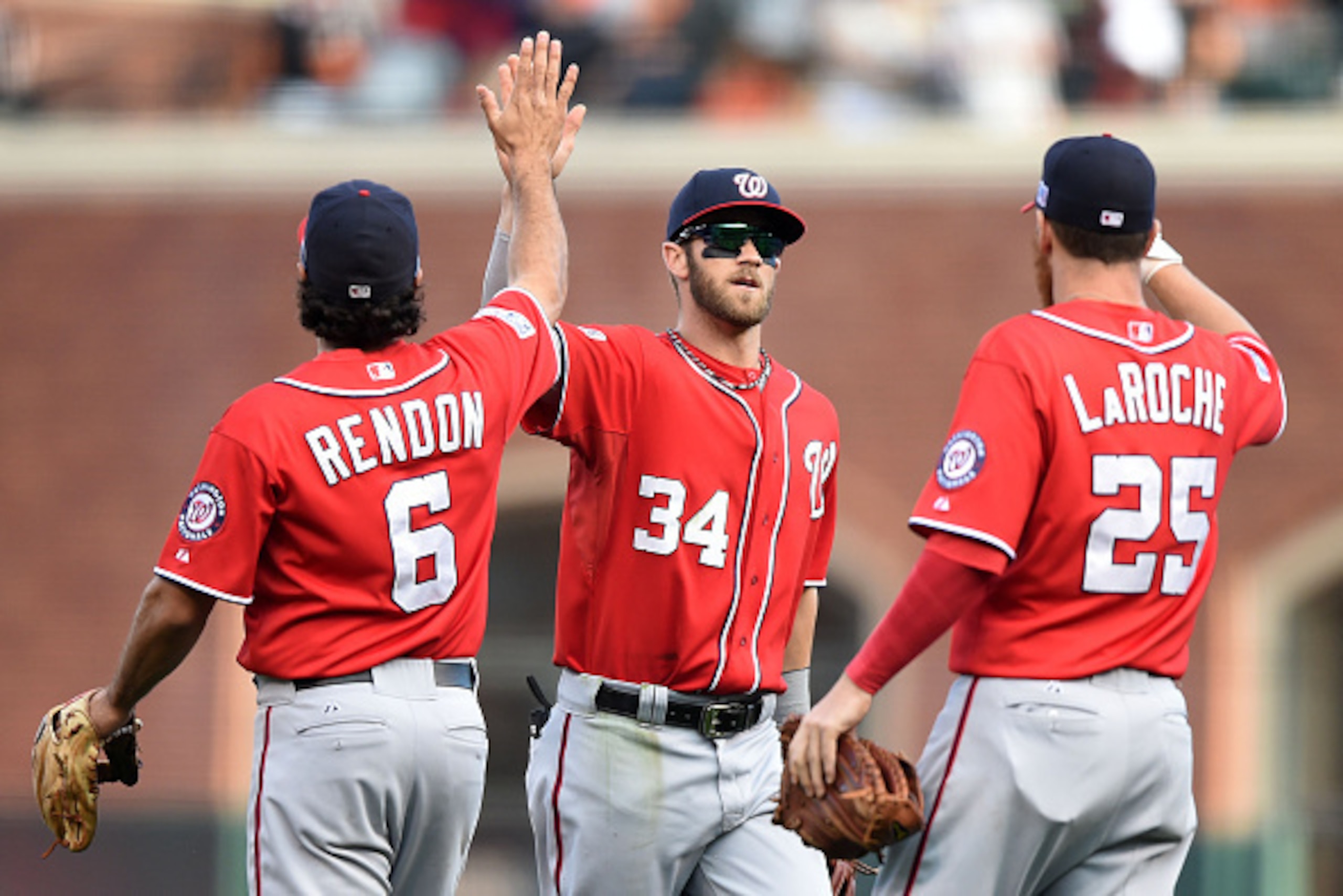 SAN FRANCISCO, CA - OCTOBER 06:  Bryce Harper #34 celebrates with Anthony Rendon #6 and Adam LaRoche #25 of the Washington Nationals after their 4 to 1 win over the San Francisco Giants during Game Three of the National League Division Series at AT&T Park