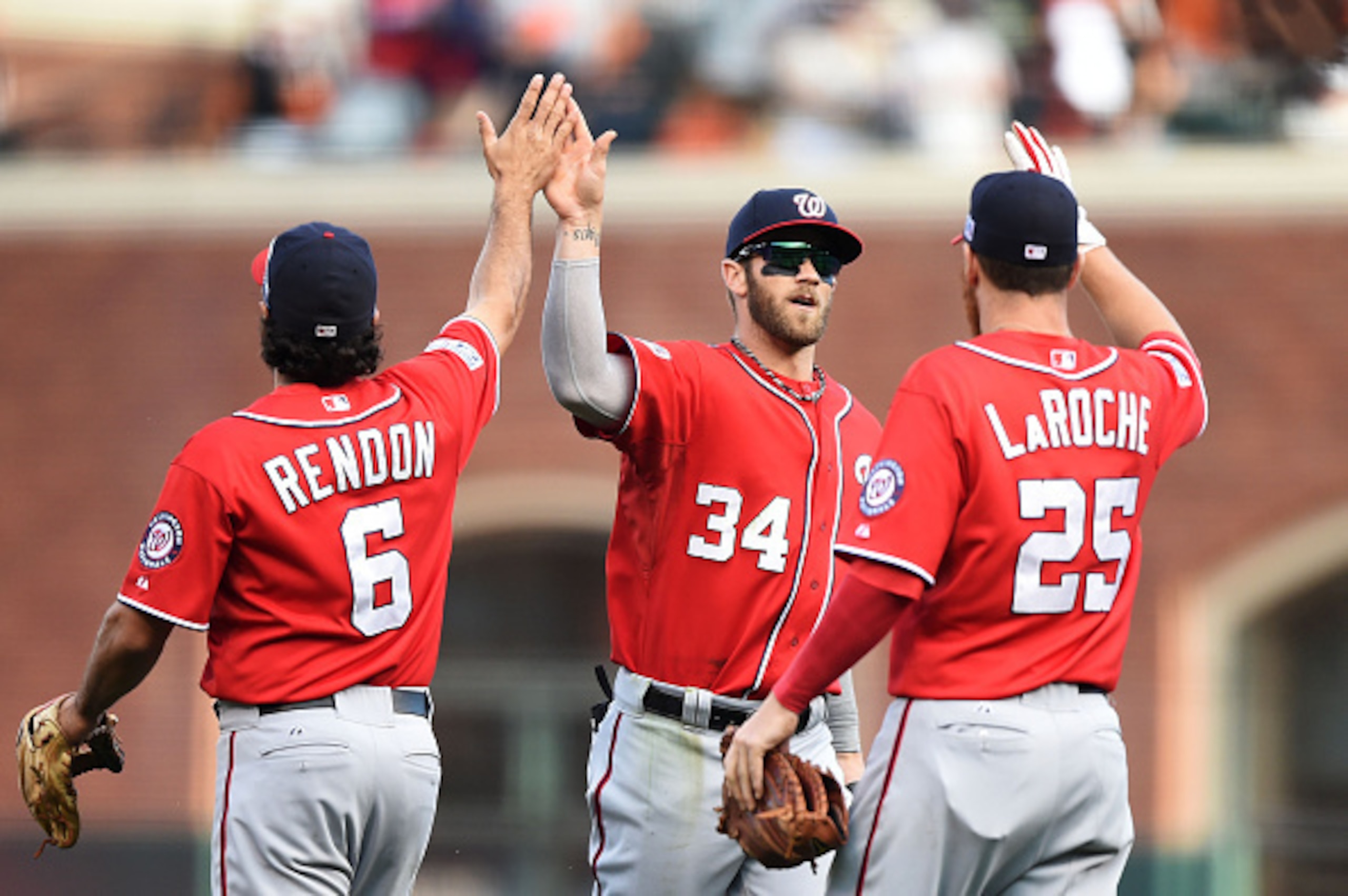 SAN FRANCISCO, CA - OCTOBER 06:  Bryce Harper #34 celebrates with Anthony Rendon #6 and Adam LaRoche #25 of the Washington Nationals after their 4 to 1 win over the San Francisco Giants during Game Three of the National League Division Series at AT&T Park