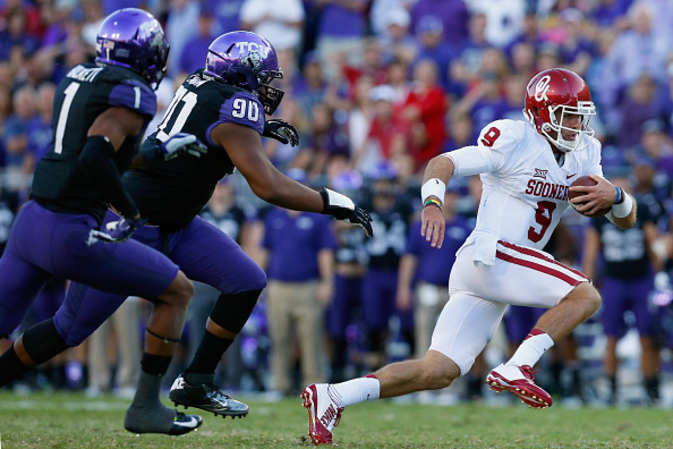 FORT WORTH, TX - OCTOBER 04:  Quarterback Trevor Knight #9 of the Oklahoma Sooners carries the ball against safety Chris Hackett #1 of the TCU Horned Frogs and defensive tackle Terrell Lathan #90 of the TCU Horned Frogs in the second half at Amon G. Carte