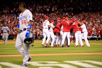 ST LOUIS, MO - OCTOBER 07:  The St. Louis Cardinals celebrate after defeating the Los Angeles Dodgers as Yasiel Puig #66 of the Los Angeles Dodgers walks off the field in Game Four of the National League Divison Series at Busch Stadium on October 7, 2014 