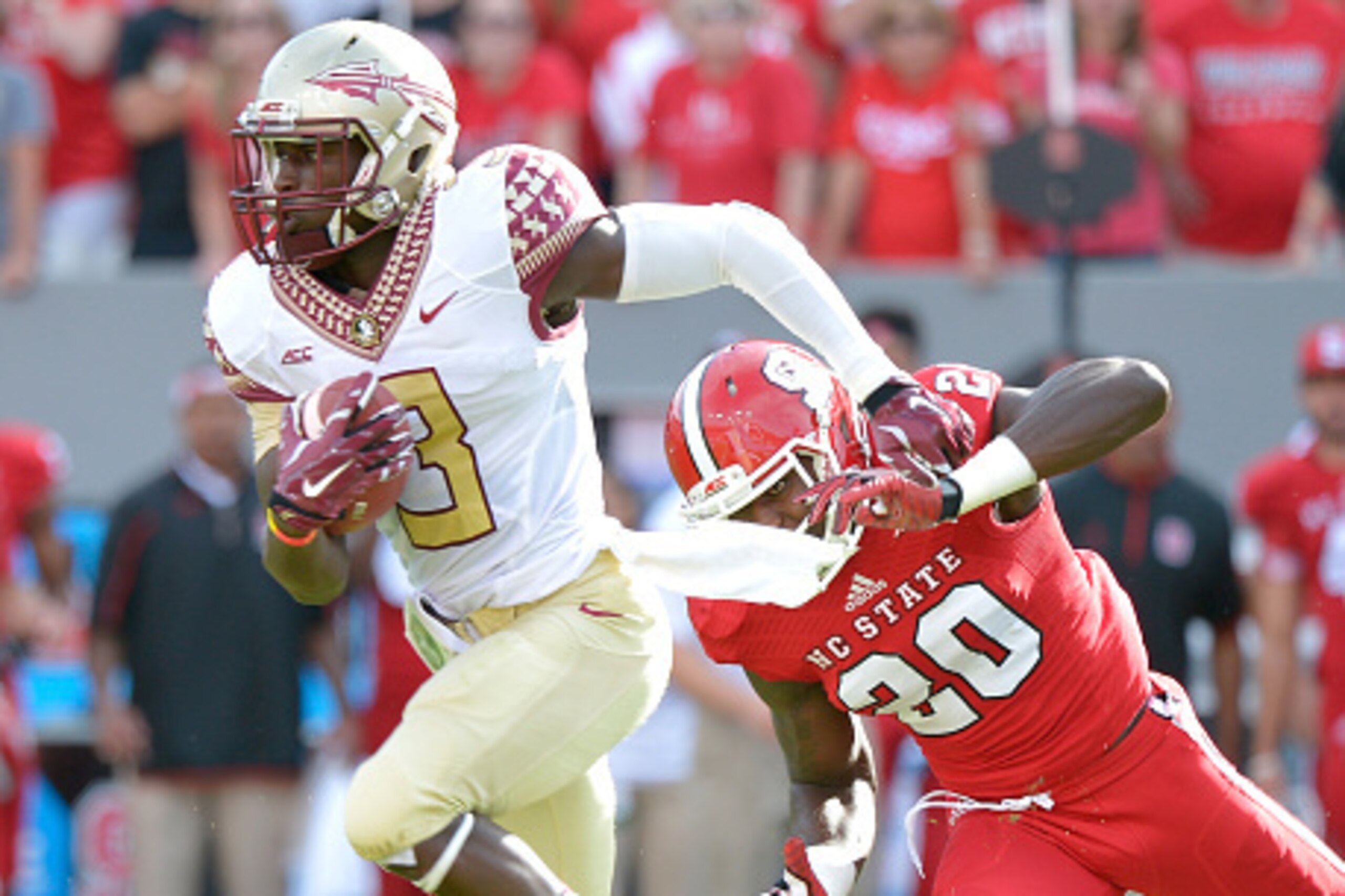 RALEIGH, NC - SEPTEMBER 27: Jesus Wilson #3 of the Florida State Seminoles breaks away from Hakim Jones #20 of the North Carolina State Wolfpack during their game at Carter-Finley Stadium on September 27, 2014 in Raleigh, North Carolina. (Photo by Grant H