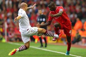 LIVERPOOL, ENGLAND - SEPTEMBER 13:  Mario Balotelli of Liverpool is tackled from Alan Hutton of Aston Villa during the Barclays Premier League match between Liverpool and Aston Villa at Anfield on September 13, 2014 in Liverpool, England.  (Photo by Alex