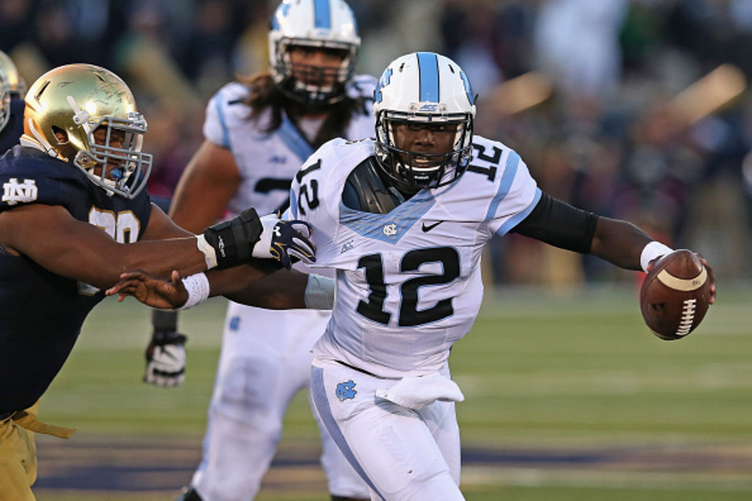 SOUTH BEND, IN - OCTOBER 11: Marquise Williams #12 of the North Carolina Tar Heels holds off Isaac Rochell #90 of the Notre Dame Fighting Irish at Notre Dame Stadium on October 11, 2014 in South Bend, Indiana. Notre Dame defeated North Carolina 50-43.  (P