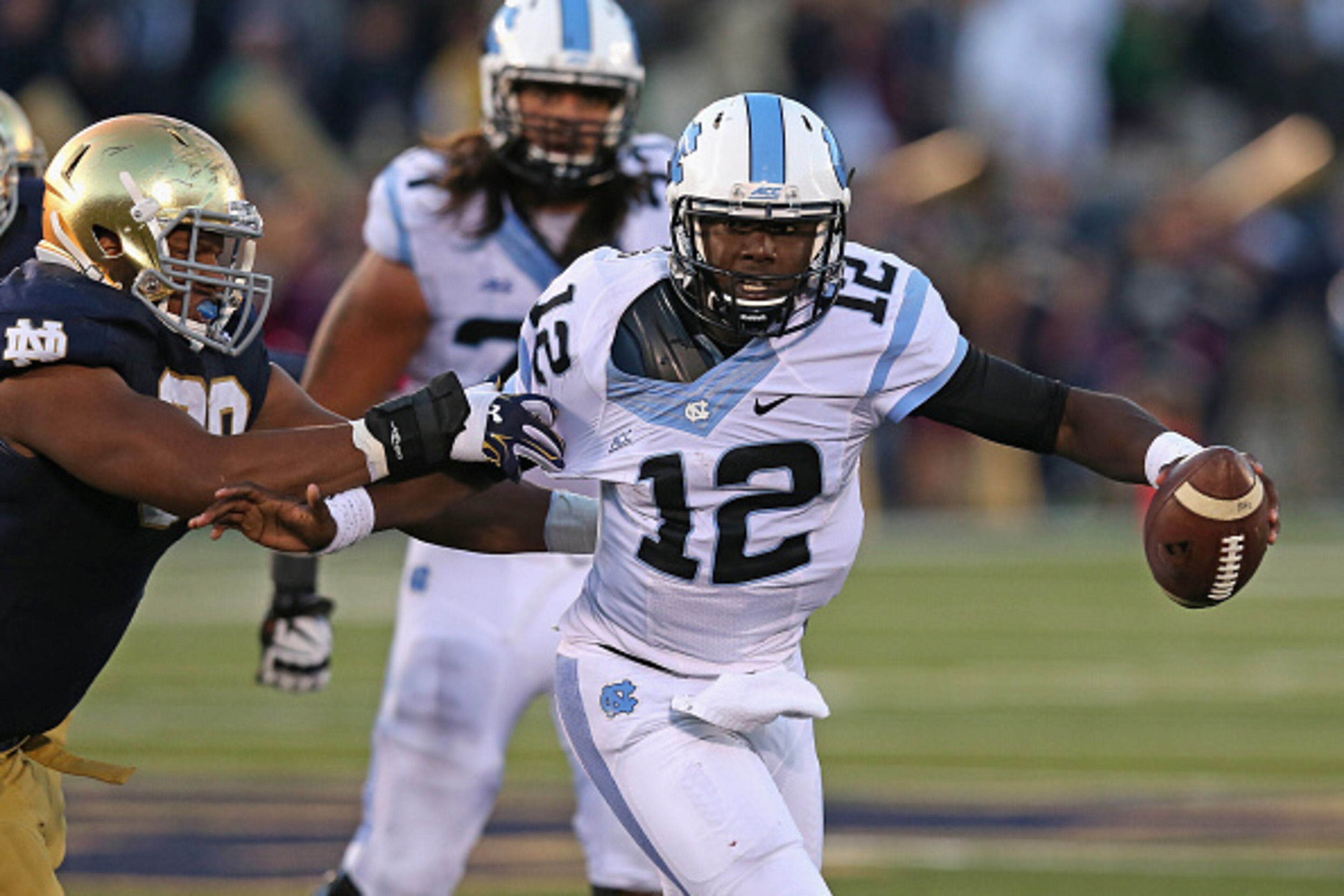 SOUTH BEND, IN - OCTOBER 11: Marquise Williams #12 of the North Carolina Tar Heels holds off Isaac Rochell #90 of the Notre Dame Fighting Irish at Notre Dame Stadium on October 11, 2014 in South Bend, Indiana. Notre Dame defeated North Carolina 50-43.  (P