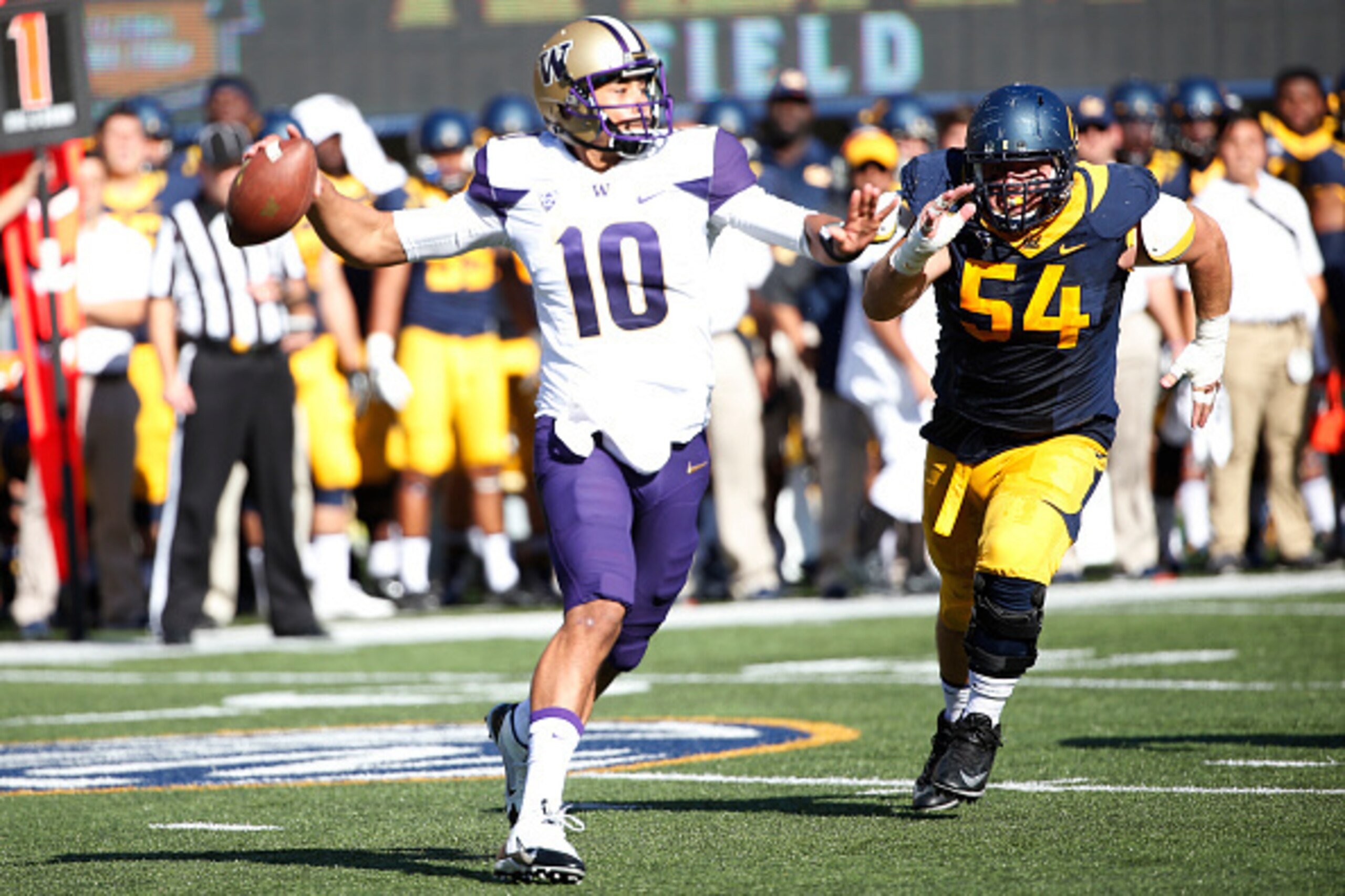 BERKELEY, CA - OCTOBER 11: Quarterback Cyler Miles #10 of the Washington Huskies looks to pass the ball as defensive tackle Austin Clark #54 pursues during the first quarter of the game on October 11, 2014 at California Memorial Stadium in Berkeley, Calif
