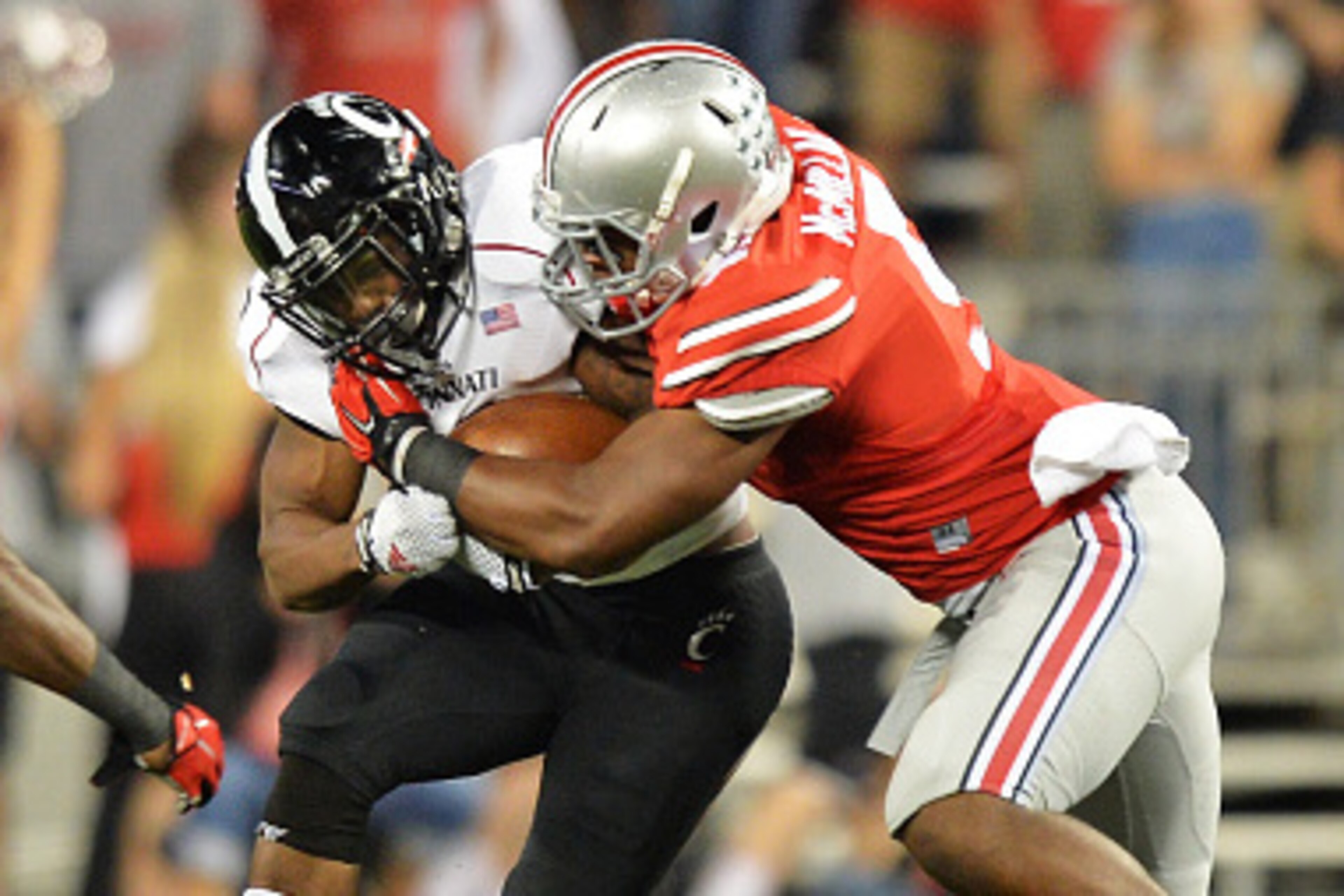COLUMBUS, OH - SEPTEMBER 27:  Hosey Williams #23 of the Cincinnati Bearcats is wrapped up after a short gain by Armani Reeves #26 and Raekwon McMillan #5 of the Ohio State Buckeyes in the third quarter at Ohio Stadium on September 27, 2014 in Columbus, Oh