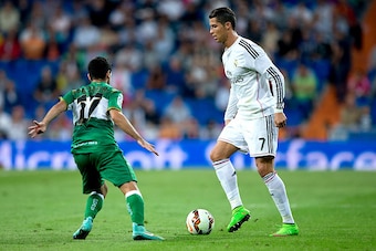 MADRID, SPAIN - SEPTEMBER 23: Cristiano Ronaldo (R) of Real Madrid CF competes for the ball with Victor Rodriguez (L) of  Elche FC during the La Liga match between Real Madrid CF and Elche CF at Estadio Santiago Bernabeu on September 23, 2014 in Madrid, S