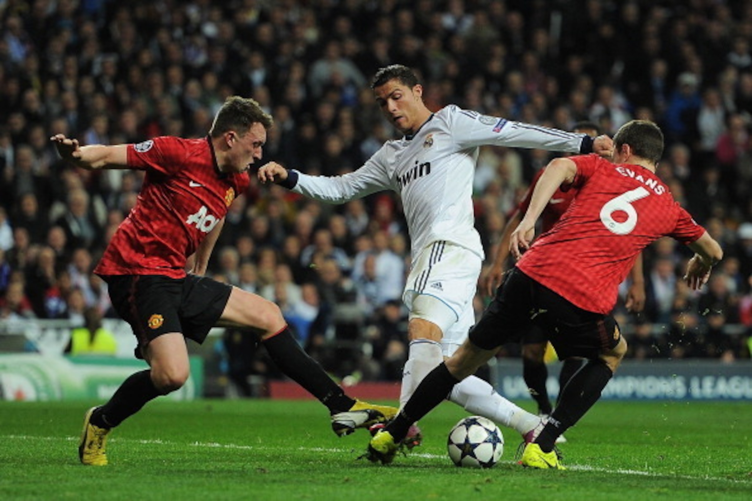MADRID, SPAIN - FEBRUARY 13:  Cristiano Ronaldo of Real Madrid is put under pressure by Jonny Evans and Phil Jones of Manchester United  during the UEFA Champions League Round of 16 first leg match between Real Madrid and Manchester United at Estadio Sant