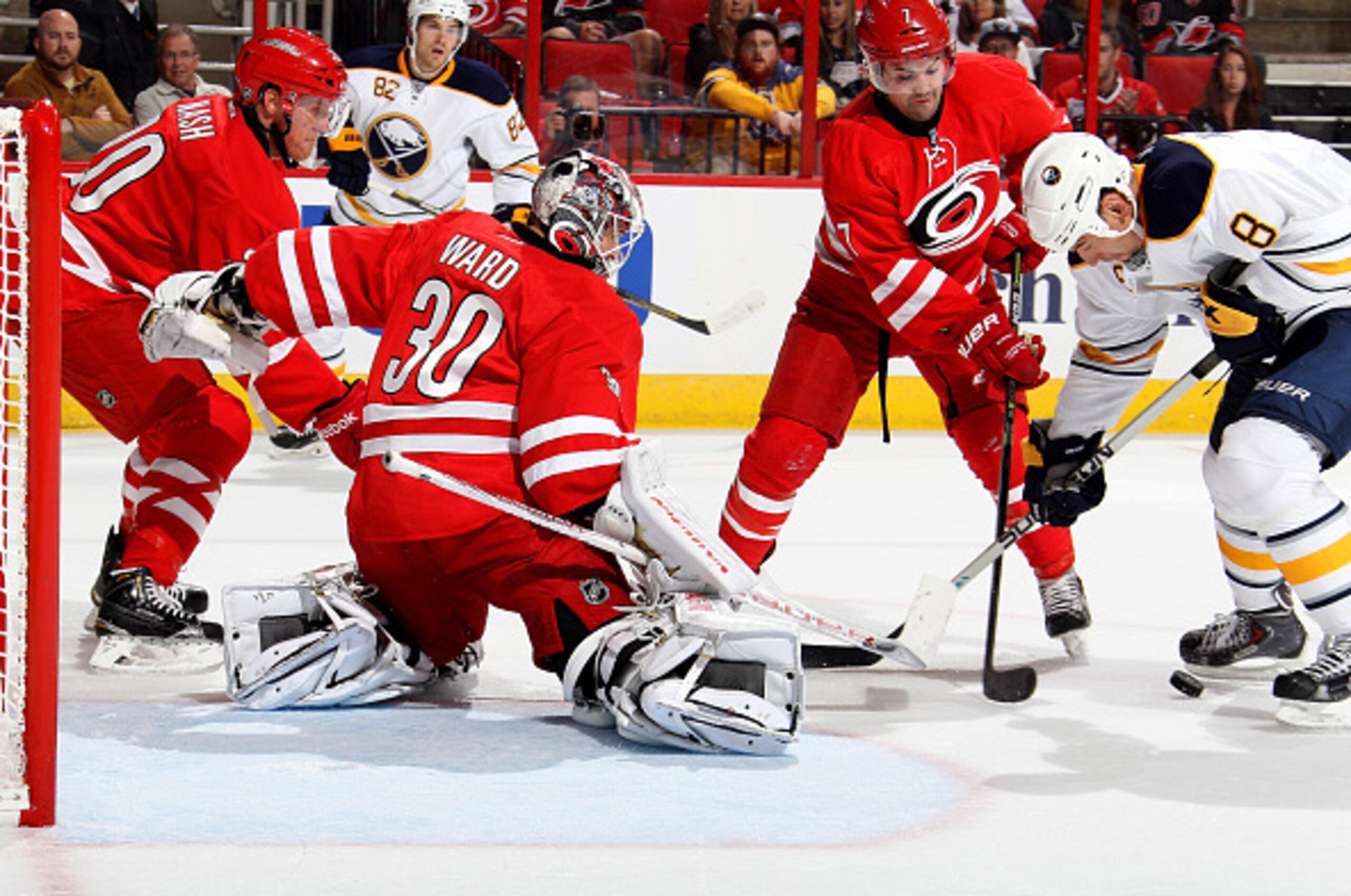 RALEIGH, NC - OCTOBER 14: Cam Ward #30 of the Carolina Hurricanes and teammates Ryan Murphy #7 and Riley Nash #20 defend the net against Cody McCormick #8 of the Buffalo Sabres during their NHL game at PNC Arena on October 14, 2014 in Raleigh, North Carol