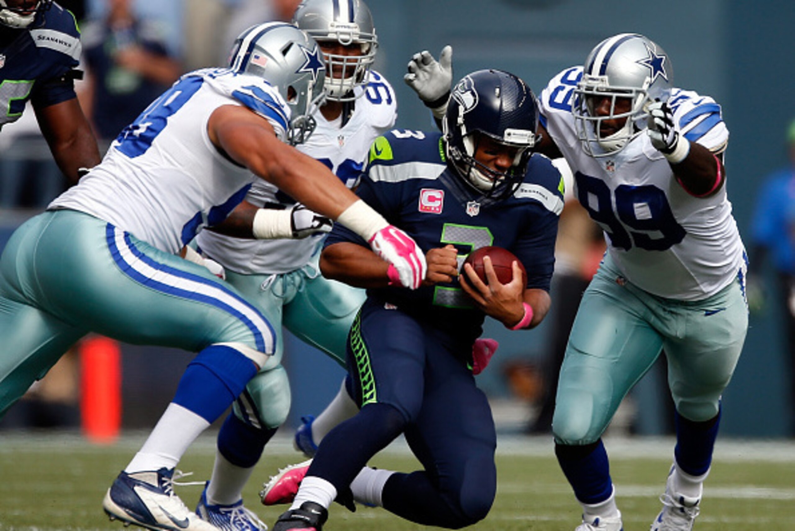 SEATTLE, WA - OCTOBER 12:  Quarterback Russell Wilson #3 of the Seattle Seahawks slides to the turf as defensive end Tyrone Crawford #98, defensive end Anthony Spencer #93 and defensive end George Selvie #99 of the Dallas Cowboys converge at CenturyLink F
