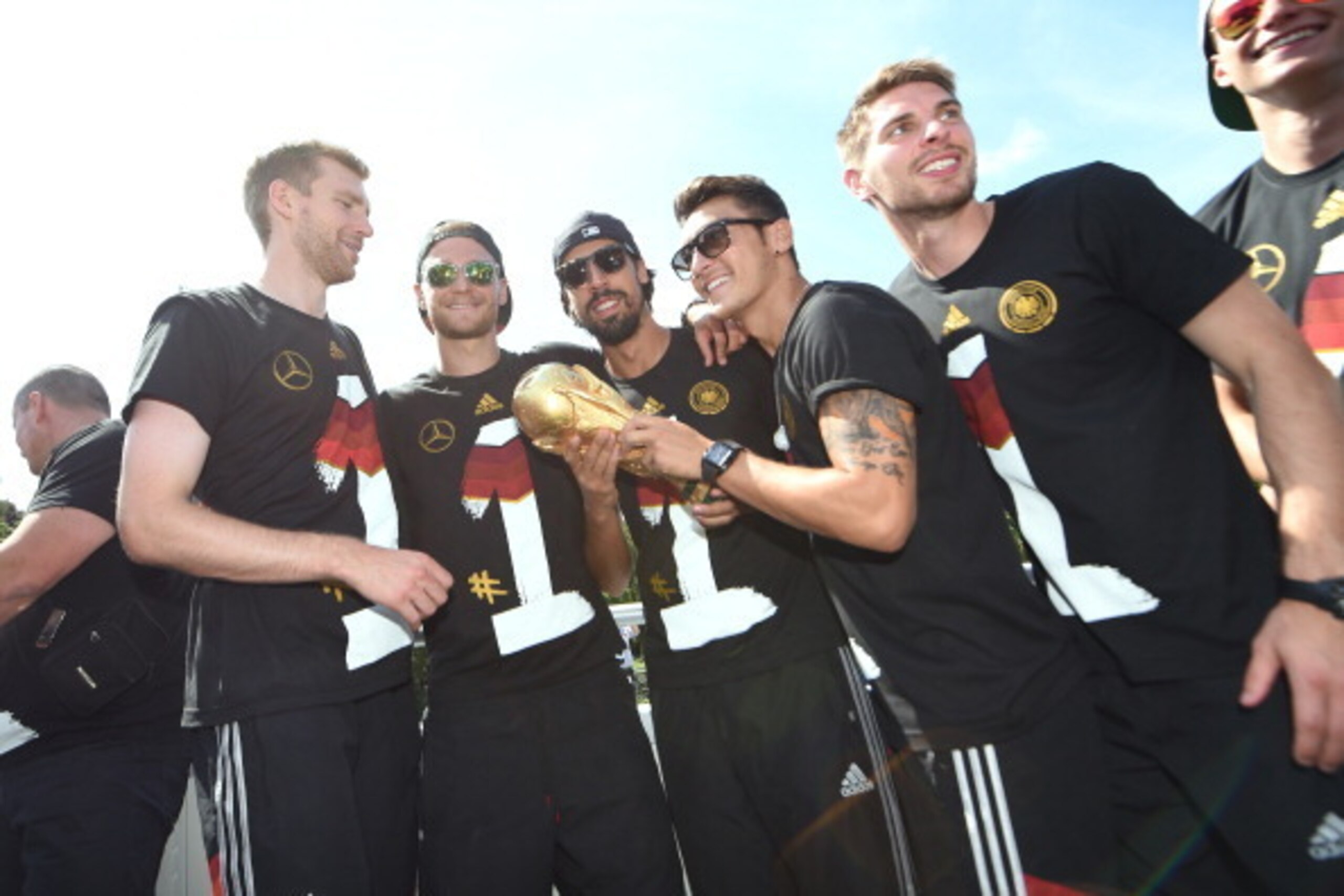 BERLIN, GERMANY - JULY 15: Per Mertersacker, Benedikt Hoewedes, Sami Khedira, Mesut Ozil and Ron-Robert Zieler  celebrate during the German team victory ceremony on July 15, 2014 in Berlin, Germany. Germany won the 2014 FIFA World Cup Brazil match against