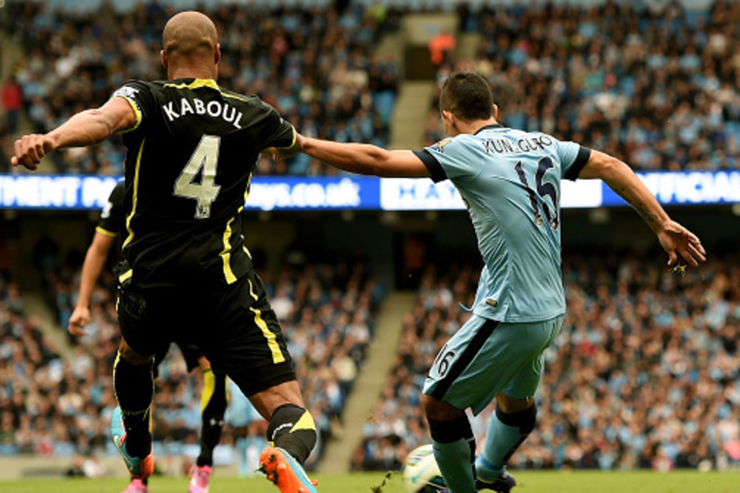 MANCHESTER, ENGLAND - OCTOBER 18:  Sergio Aguero of Manchester City shoots past Younes Kaboul of Spurs to score the opening goal during the Barclays Premier League match between Manchester City and Tottenham Hotspur at Etihad Stadium on October 18, 2014 i