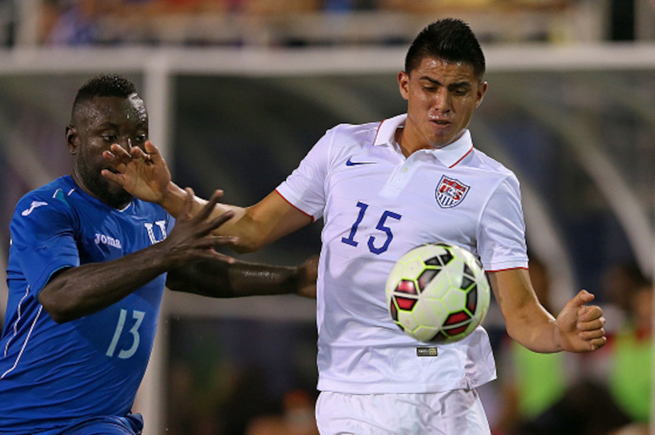 BOCA RATON, FL - OCTOBER 14: Joe Corona #15 of the USA fights for a ball with Wilmer Cristanto #13 of Honduras during a game at FAU Stadium on October 14, 2014 in Boca Raton, Florida.  (Photo by Mike Ehrmann/Getty Images)