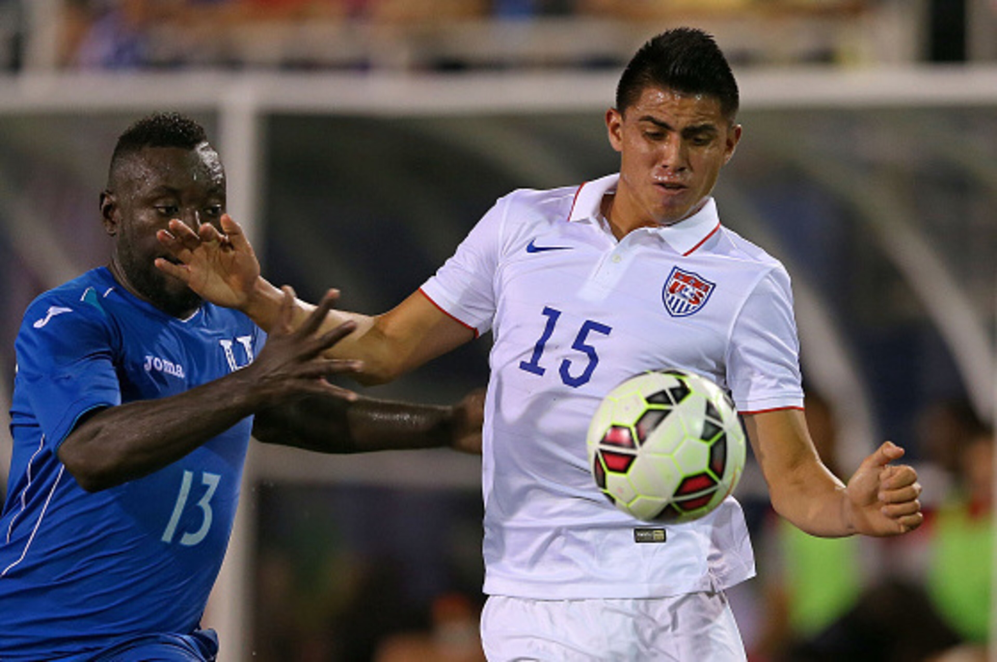 BOCA RATON, FL - OCTOBER 14: Joe Corona #15 of the USA fights for a ball with Wilmer Cristanto #13 of Honduras during a game at FAU Stadium on October 14, 2014 in Boca Raton, Florida.  (Photo by Mike Ehrmann/Getty Images)