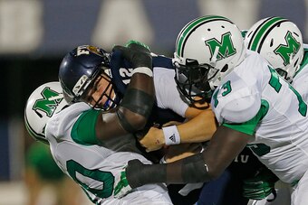 MIAMI, FL - OCTOBER 18: Alex McGough # 12 of the Florida International Panthers is sacked by Arnold Blackmon #90 and Joe Massaquoi #73 of the Marshall Thundering Herd on October 18, 2014 at FIU Stadium in Miami, Florida. Marshall defeated Florida Internat