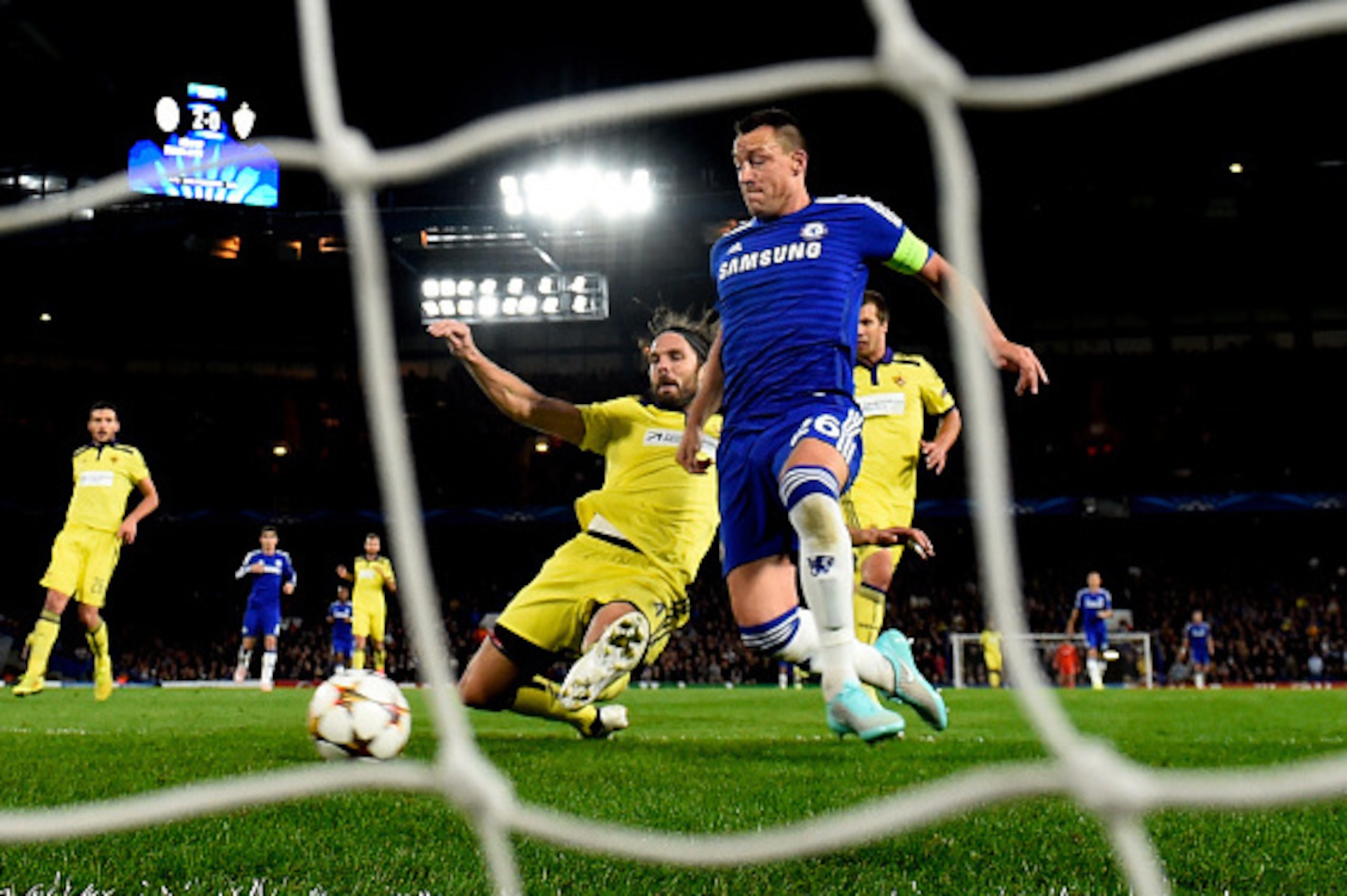 LONDON, ENGLAND - OCTOBER 21: John Terry of Chelsea scores his team's third goal despite the attentions of Marko Suler of Maribor during the UEFA Champions League Group G match between Chelsea FC and NK Maribor at Stamford Bridge on October 21, 2014 in Lo