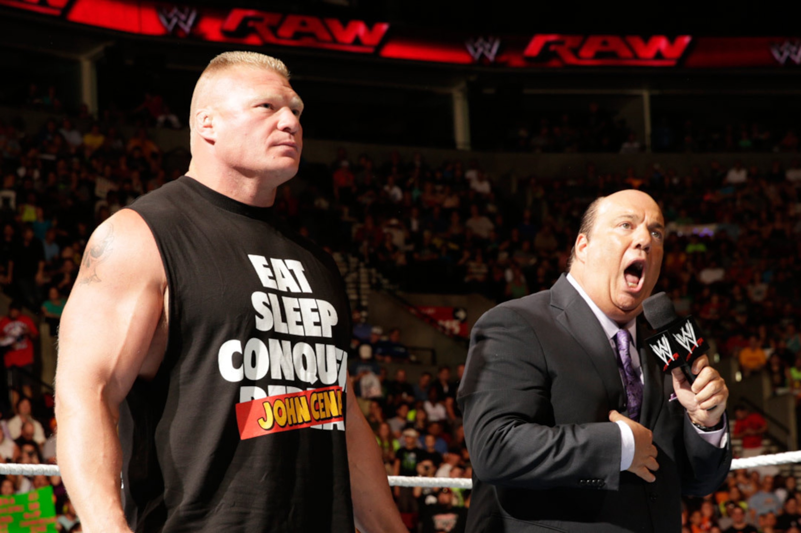 Brock Lesnar listens as Paul Heyman addresses the crowd.