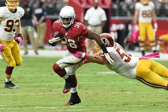 GLENDALE, AZ - OCTOBER 12: Running back Andre Ellington #38 of the Arizona Cardinals slips by linebacker Will Compton #51 of the Washington Redskins during the second half of the NFL game at University of Phoenix Stadium on October 12, 2014 in Glendale, A