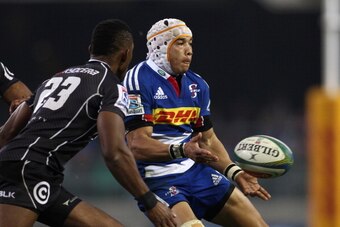 CAPE TOWN, SOUTH AFRICA - JULY 12: Cheslin Kolbe of the Stormers gets his pass away as Tonderai Chavhanga of the Sharks attempts to make the tackle during the Super Rugby match between DHL Stormers and Cell C Sharks at DHL Newlands Stadium on July 12, 201