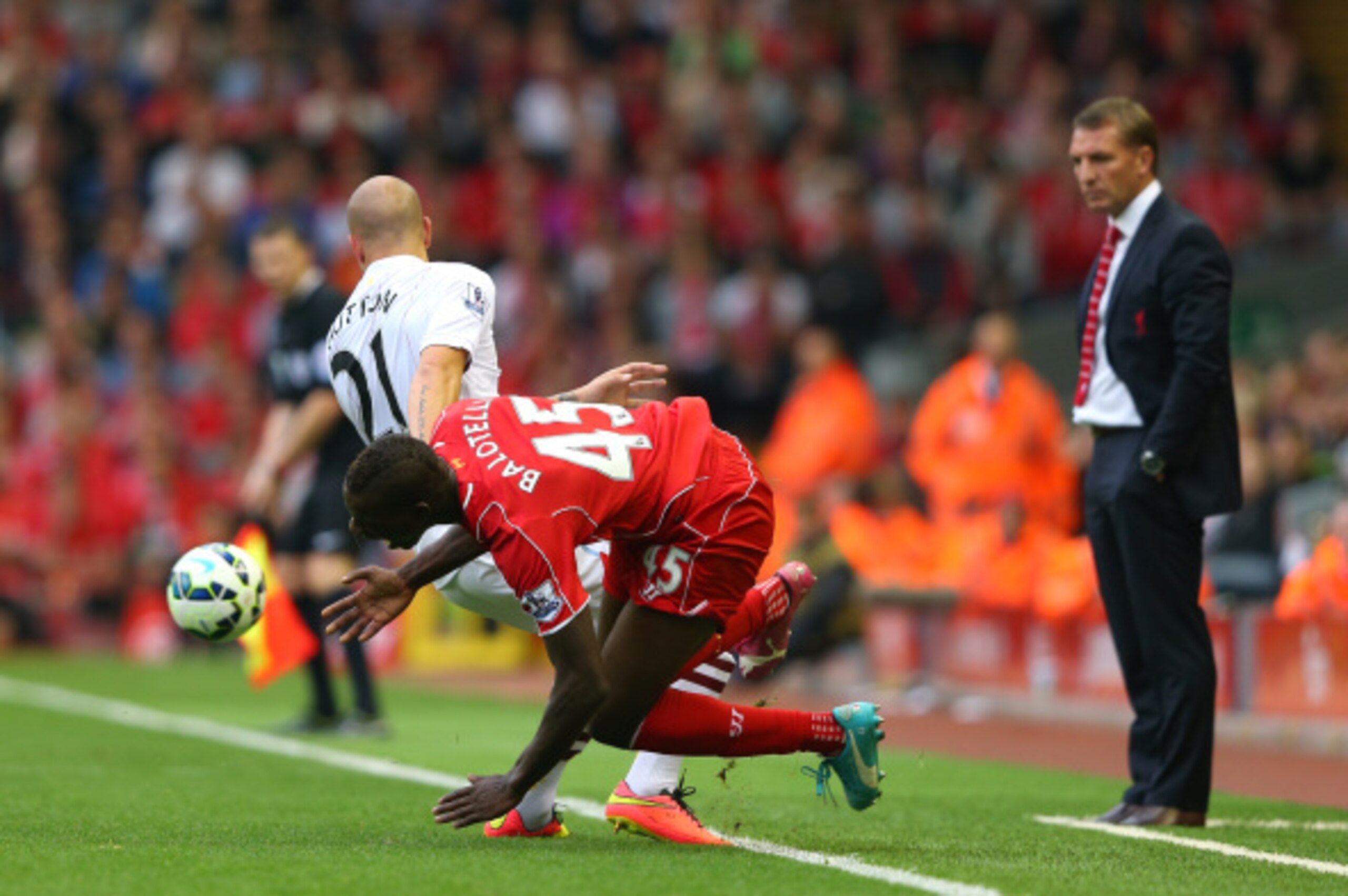 LIVERPOOL, ENGLAND - SEPTEMBER 13: Mario Balotelli of Liverpool falls after a heavy challenge from Alan Hutton of Aston Villa as Brendan Rodgers looks on during the Barclays Premier League match between Liverpool and Aston Villa at Anfield on September 1 LIVERPOOL, ENGLAND - SEPTEMBER 13: Mario Balotelli of Liverpool falls after a heavy challenge from Alan Hutton of Aston Villa as Brendan Rodgers looks on during the Barclays Premier League match between Liverpool and Aston Villa at Anfield on September 1