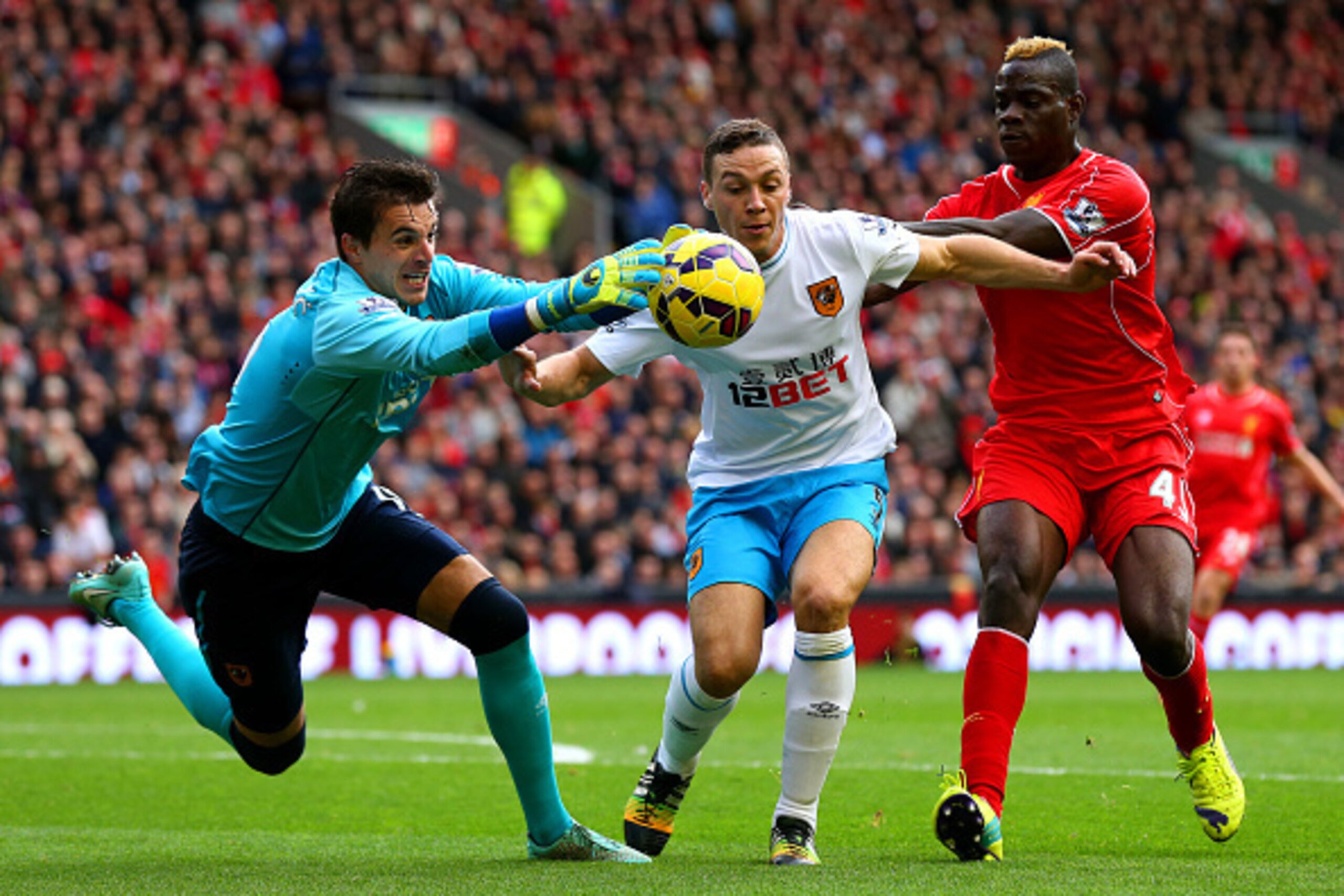 LIVERPOOL, ENGLAND - OCTOBER 25:  Eldin Jakupovic of Hull City claims the ball in front of team-mate James Chester and Mario Balotelli of Liverpool during the Barclays Premier League match between Liverpool and Hull City at Anfield on October 25, 2014 in 