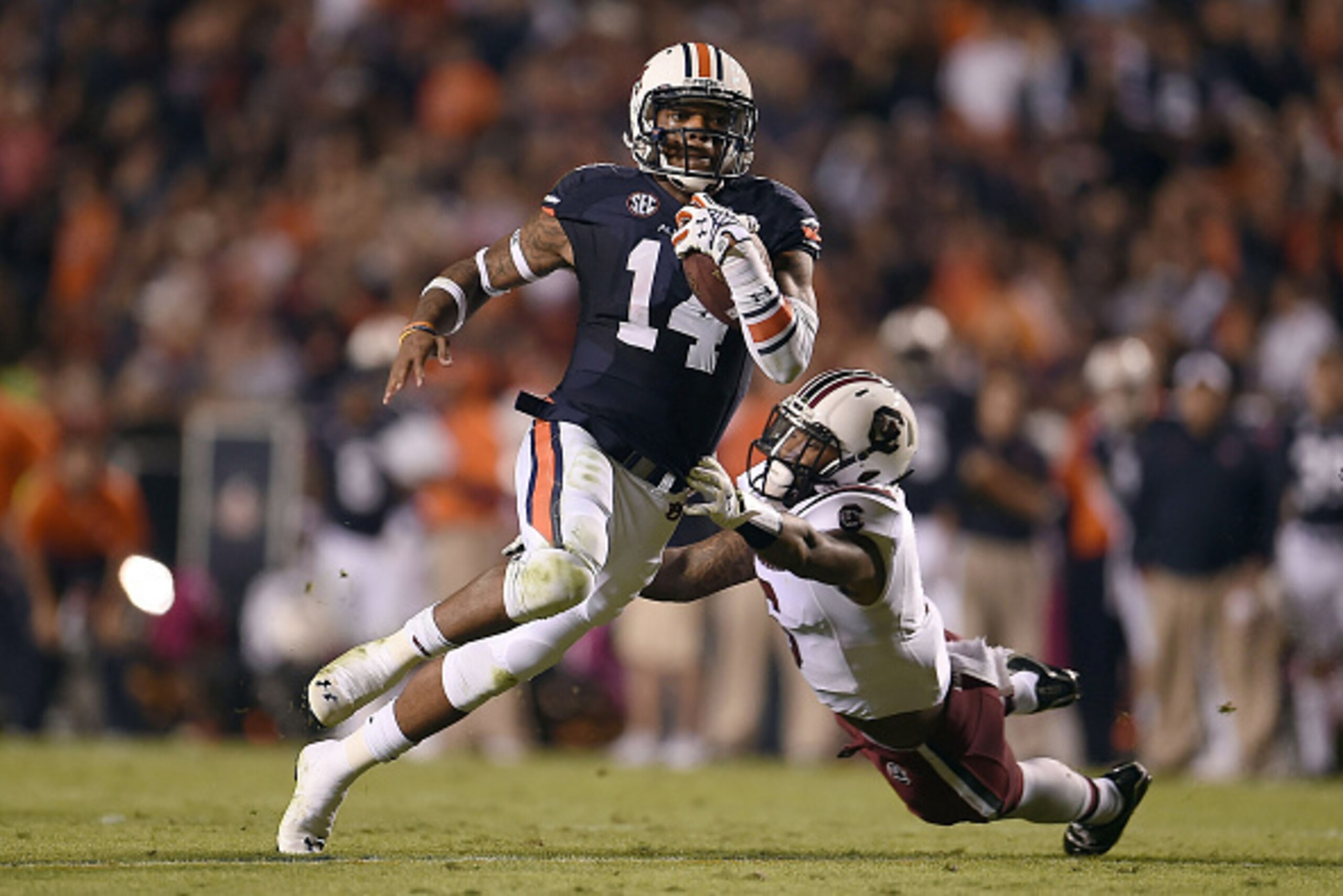 AUBURN, AL - OCTOBER 25:  Nick Marshall #14 of the Auburn Tigers avoids a tackle by Chris Moody #6 of the South Carolina Gamecocks during the second quarter of a game at Jordan Hare Stadium on October 25, 2014 in Auburn, Alabama.  (Photo by Stacy Revere/G