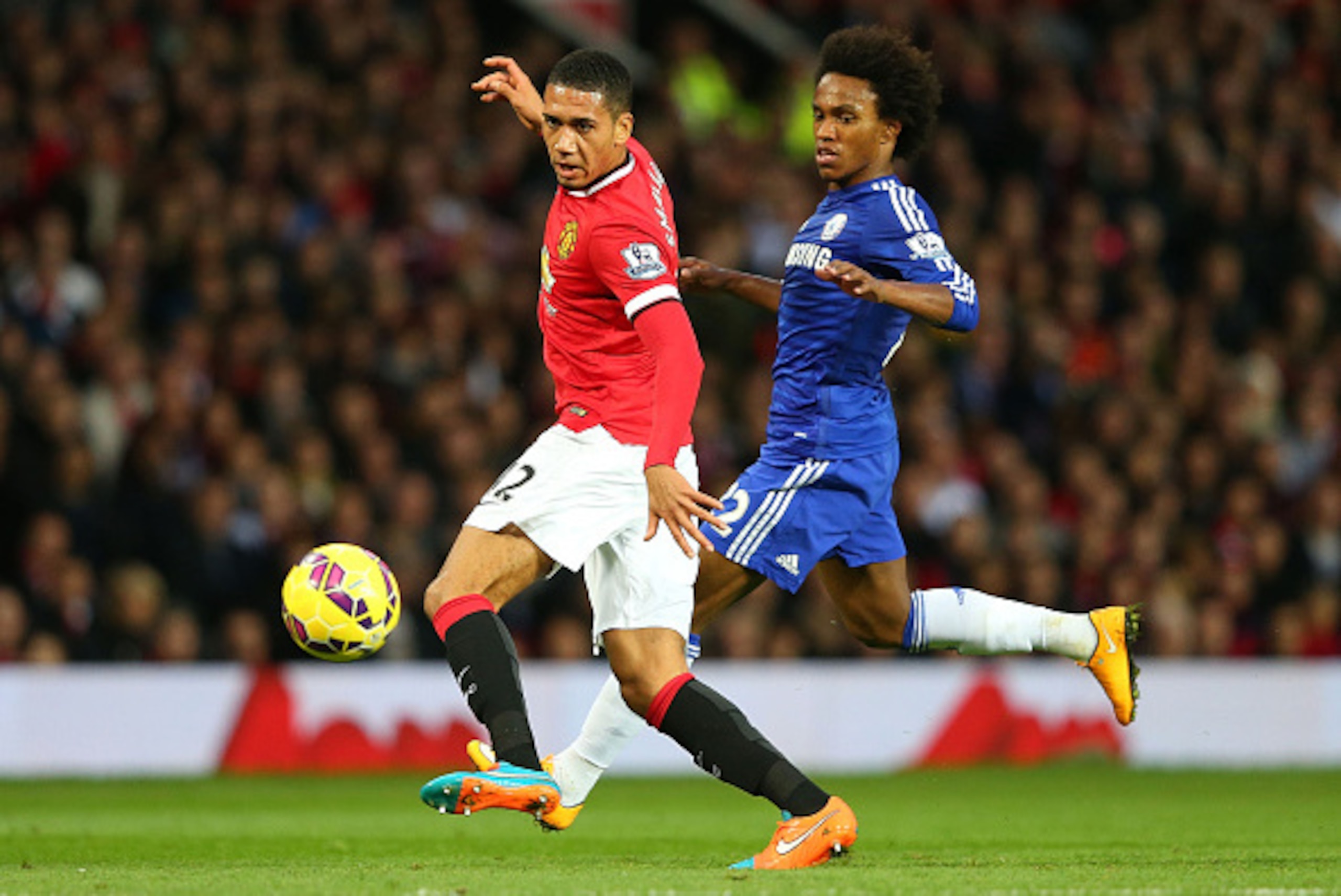 MANCHESTER, ENGLAND - OCTOBER 26:  Chris Smalling of Manchester United competes with Willian of Chelsea during the Barclays Premier League match between Manchester United and Chelsea at Old Trafford on October 26, 2014 in Manchester, England.  (Photo by A