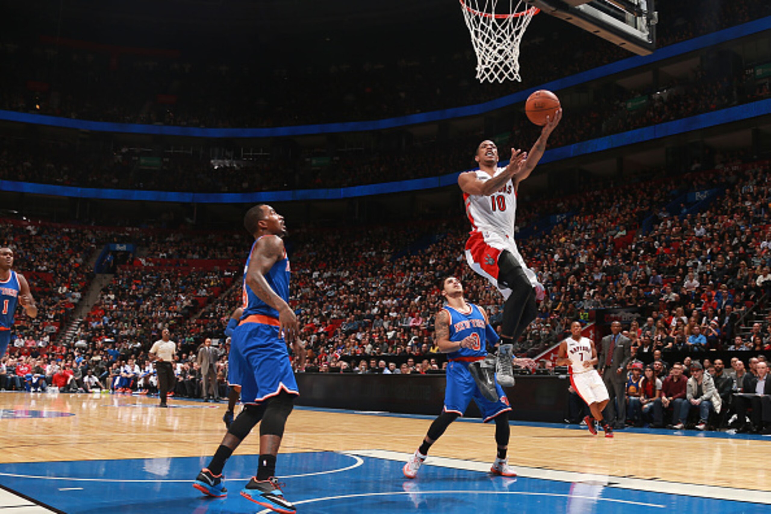 MONTREAL, QC - OCTOBER 24: DeMar DeRozan #10 of the Toronto Raptors drives to the basket past J.R. Smith #8 and Shane Larkin #0 both of the New York Knicks during their pre-season NBA game at the Bell Centre on October 24, 2014 in Montreal, Quebec, Canada