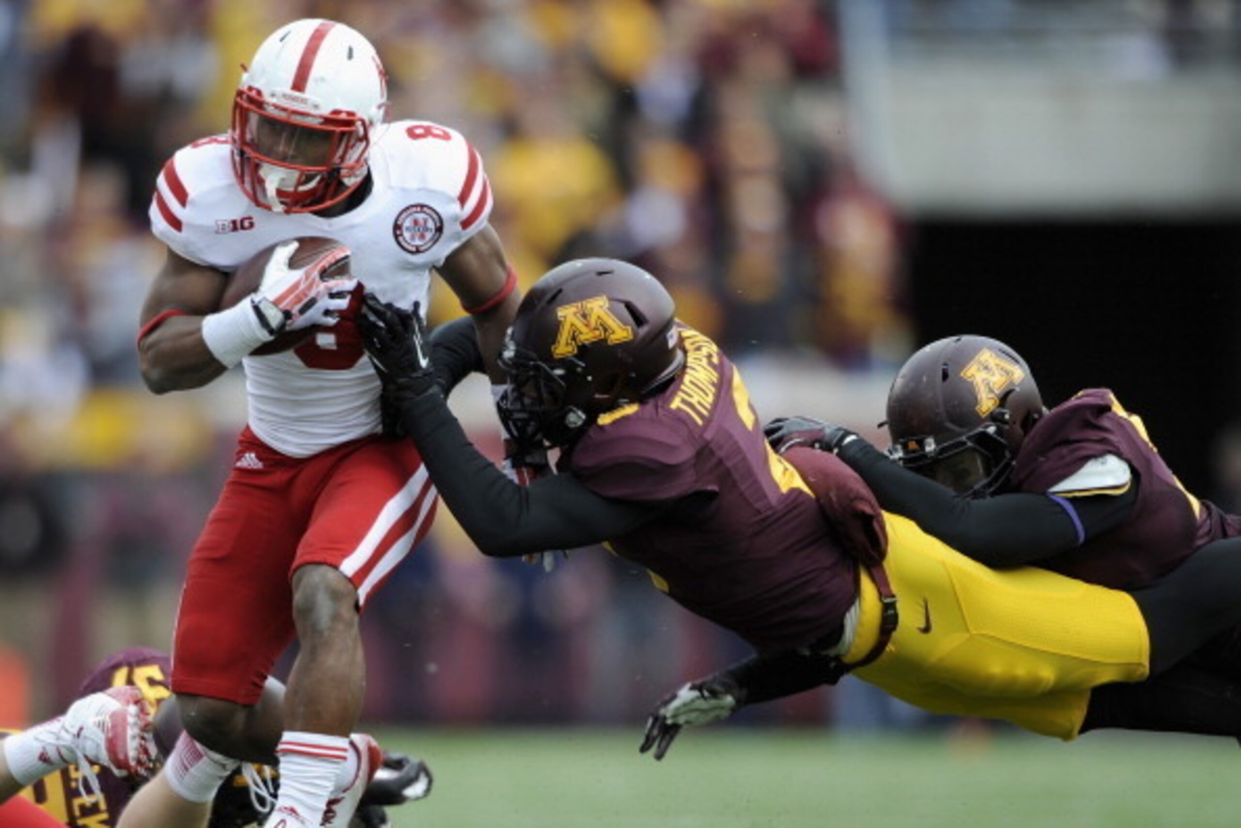MINNEAPOLIS, MN - OCTOBER 26: Ameer Abdullah #8 of the Nebraska Cornhuskers is pushed out of bounds by Cedric Thompson #2 and Alex Keith #91 of the Minnesota Golden Gophers during the third quarter of the game on October 26, 2013 at TCF Bank Stadium in Mi