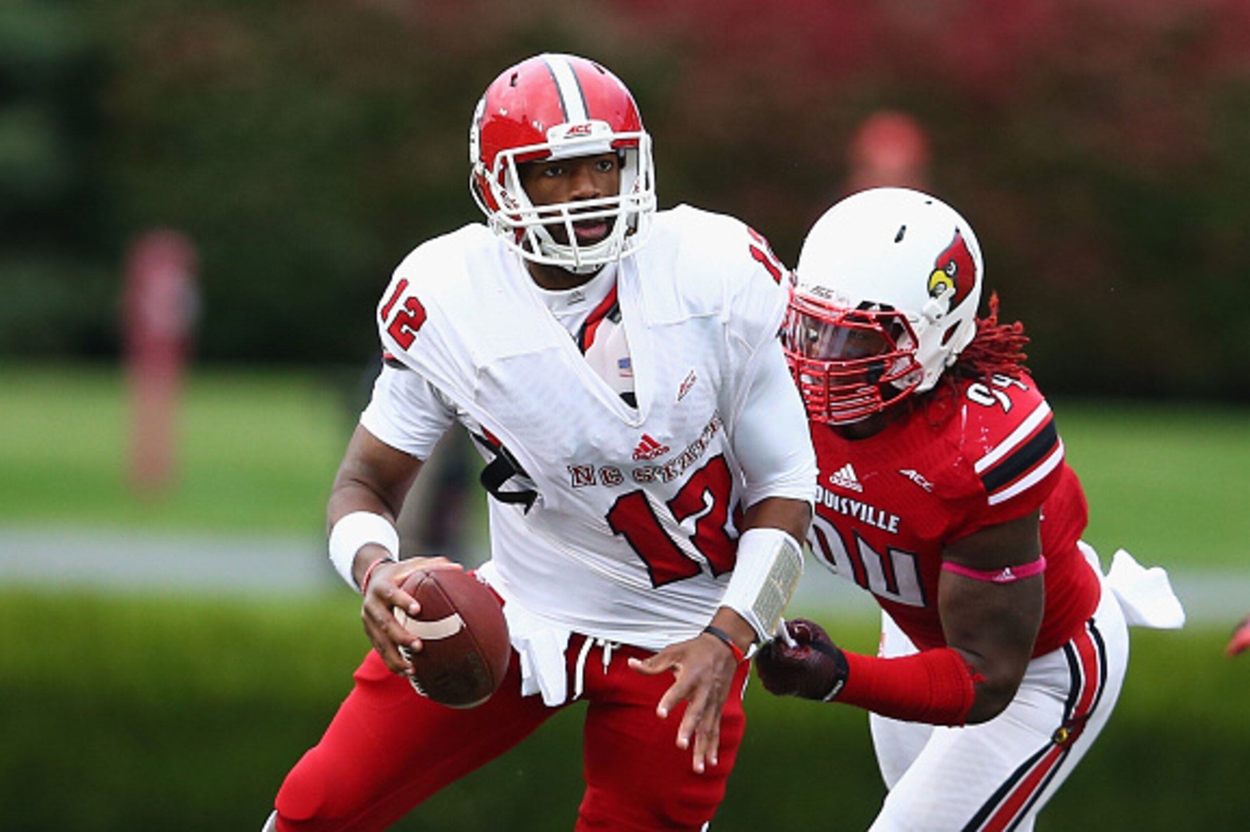 LOUISVILLE, KY - OCTOBER 18:  Lorenzo Mauldin #94 of the Louisville Cardinals grabs onto Jacoby Brissett #12 of the North Carolina State Wolfpack during the game at Papa John's Cardinal Stadium on October 18, 2014 in Louisville, Kentucky.  (Photo by Andy 