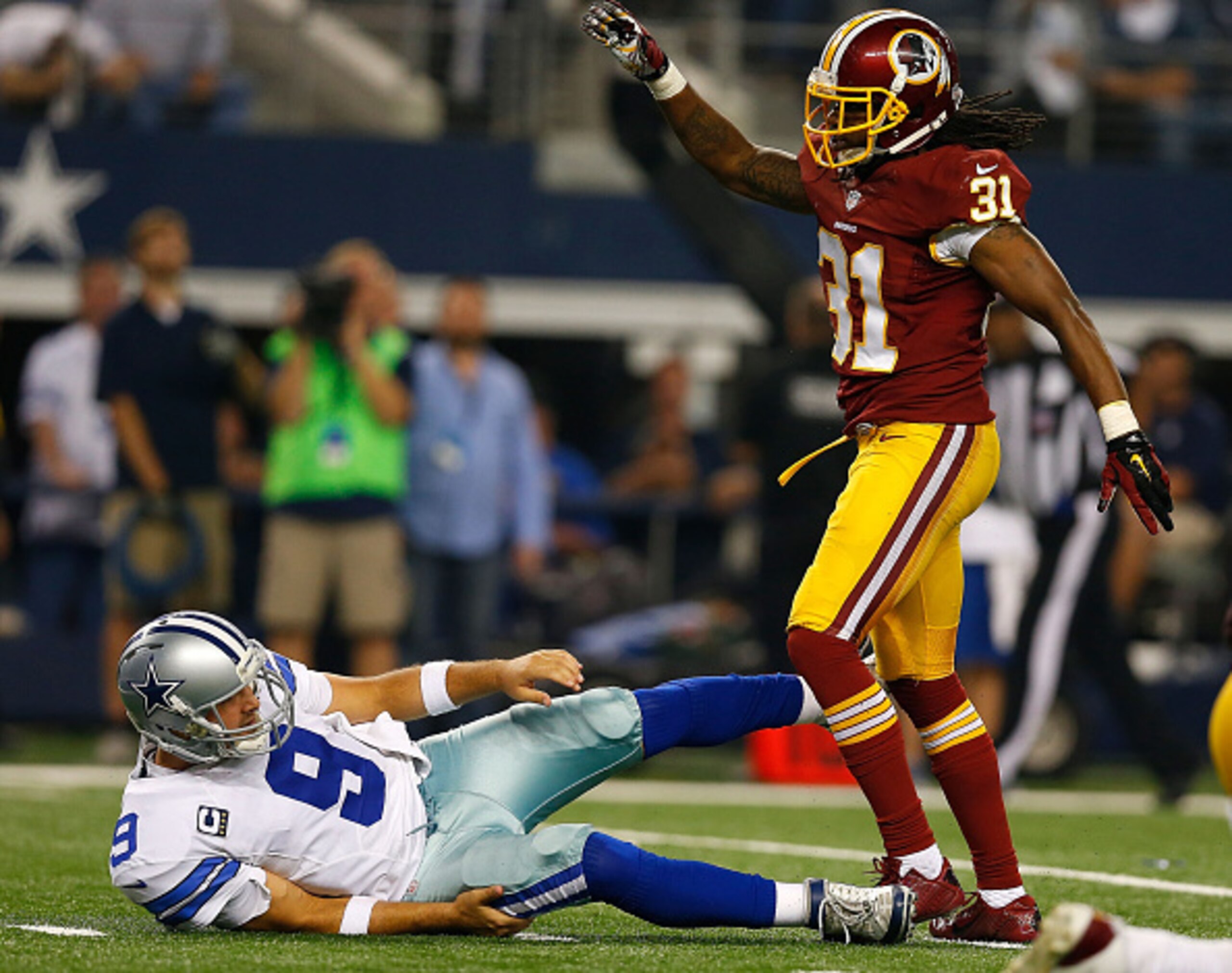 ARLINGTON, TX - OCTOBER 27:  Tony Romo #9 of the Dallas Cowboys is knocked to the ground by Brandon Meriweather #31 of the Washington Redskins during the second half at AT&T Stadium on October 27, 2014 in Arlington, Texas.  (Photo by Tom Pennington/Getty 