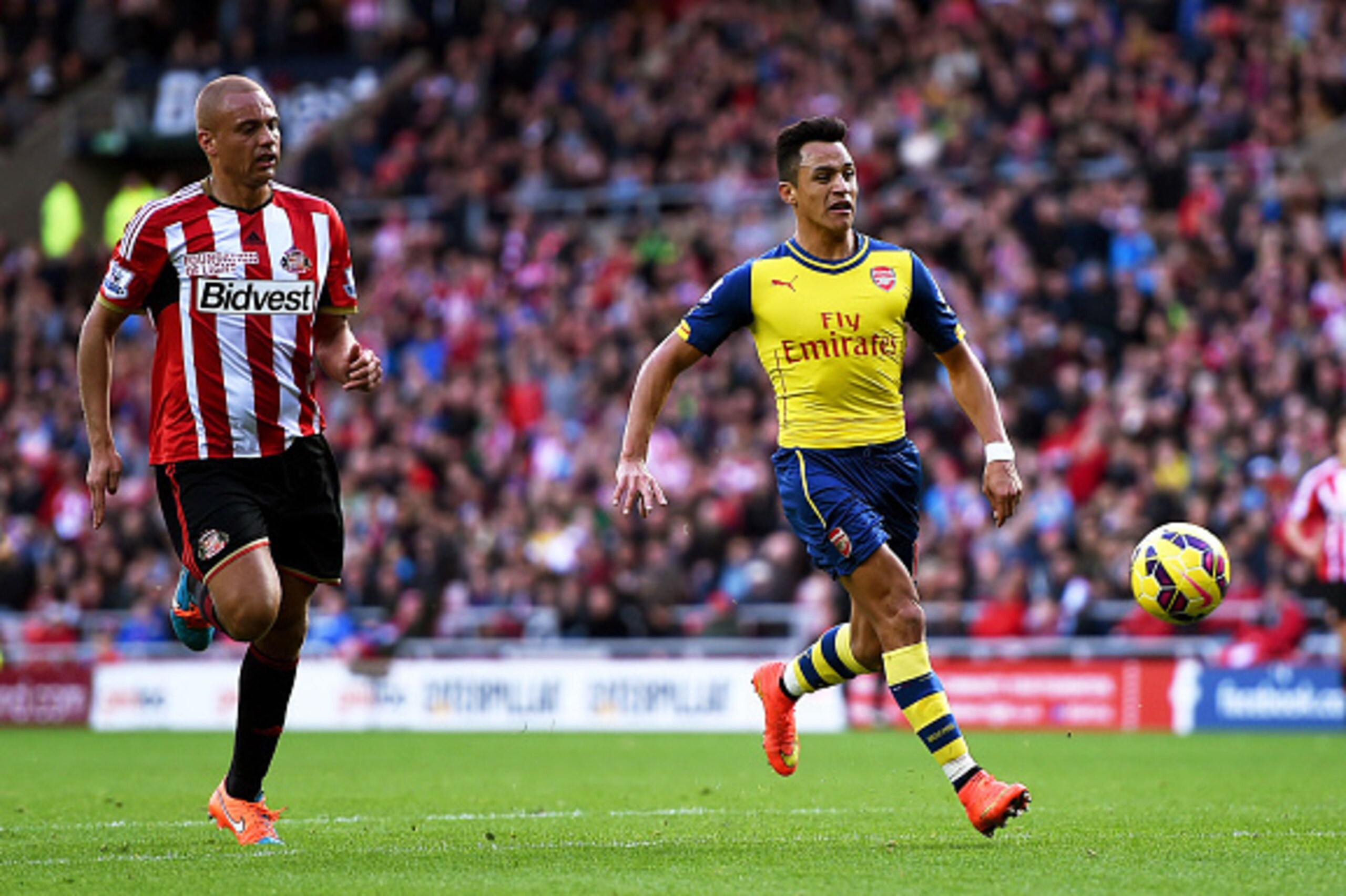 SUNDERLAND, ENGLAND - OCTOBER 25:  Alexis Sanchez of Arsenal outpaces Wes Brown of Sunderland to score the opening goal during the Barclays Premier League match between Sunderland and Arsenal at the Stadium of Light on October 25, 2014 in Sunderland, Engl