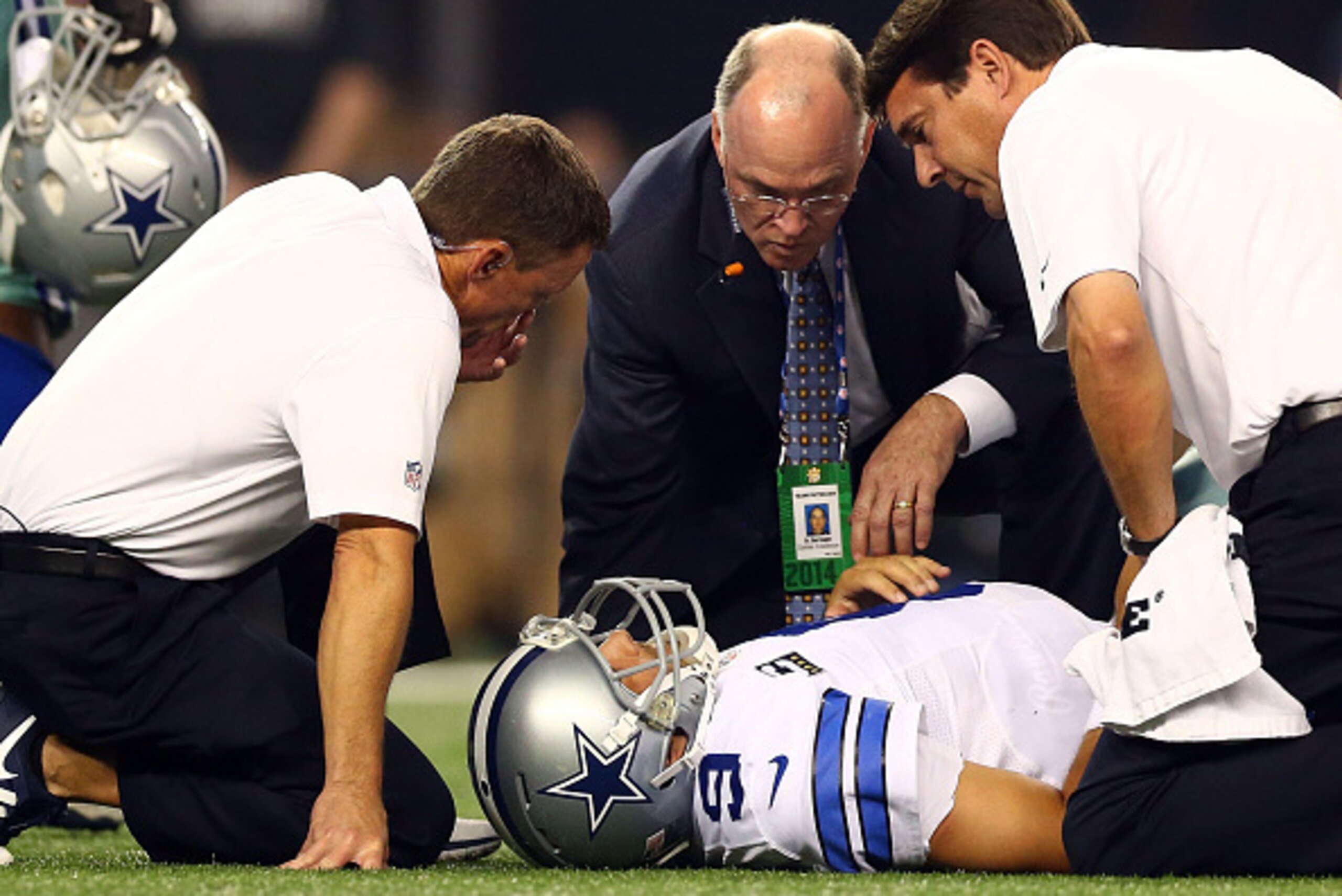 ARLINGTON, TX - OCTOBER 27:  Tony Romo #9 of the Dallas Cowboys is attended to by team personnel after being sacked by Keenan Robinson #52 of the Washington Redskins during the second half at AT&T Stadium on October 27, 2014 in Arlington, Texas.  (Photo b