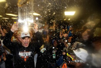 KANSAS CITY, MO - OCTOBER 29:  Bruce Bochy #15 of the San Francisco Giants celebrates with The Commissioner's Trophy in the locker room after a 3-2 win over the Kansas City Royals in Game Seven of the 2014 World Series at Kauffman Stadium on October 29, 2