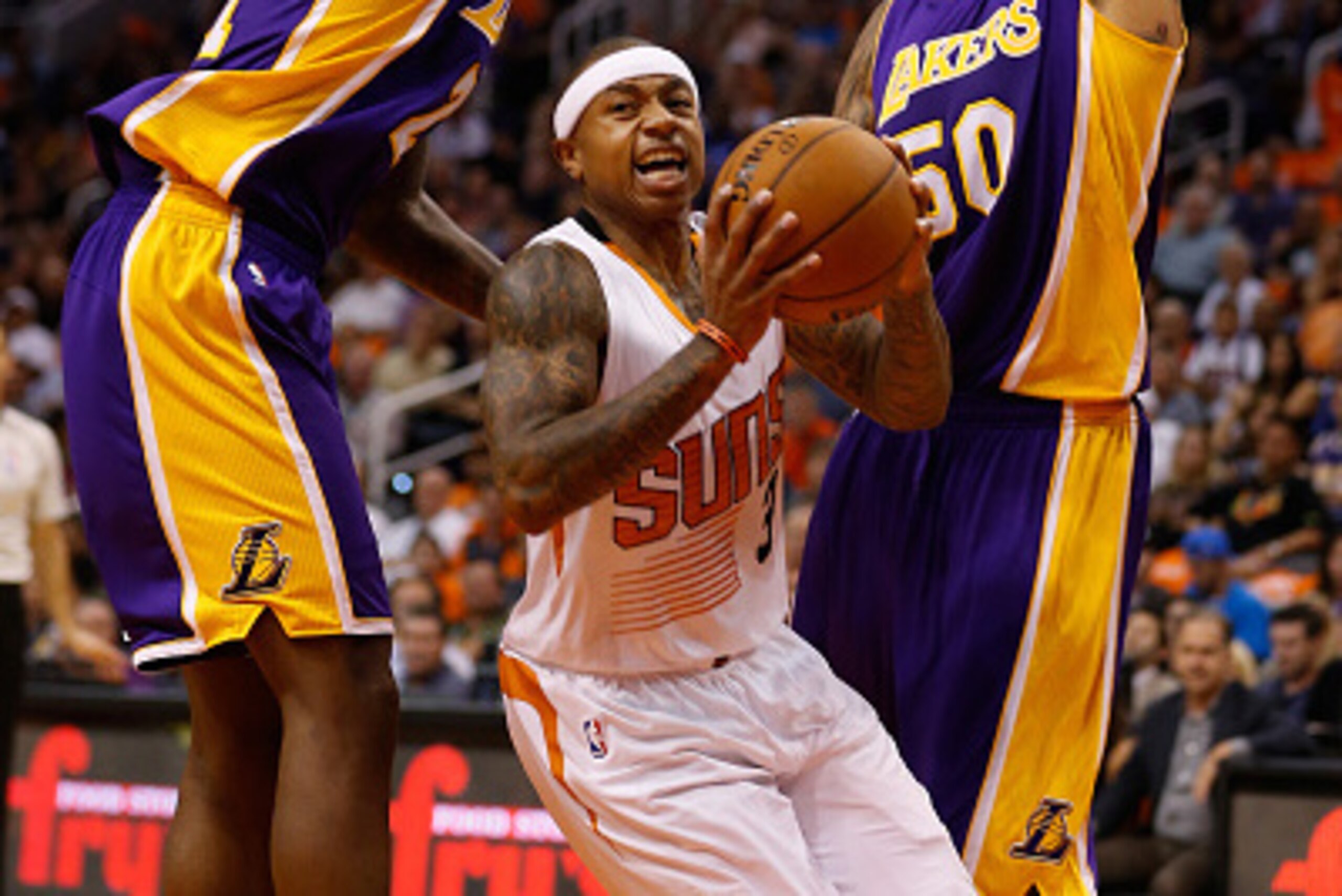 PHOENIX, AZ - OCTOBER 29:  Isaiah Thomas #3 of the Phoenix Suns drives the ball pasat Ed Davis #21 and Robert Sacre #50 of the Los Angeles Lakers during the second half of the NBA game at US Airways Center on October 29, 2014 in Phoenix, Arizona.  The Sun