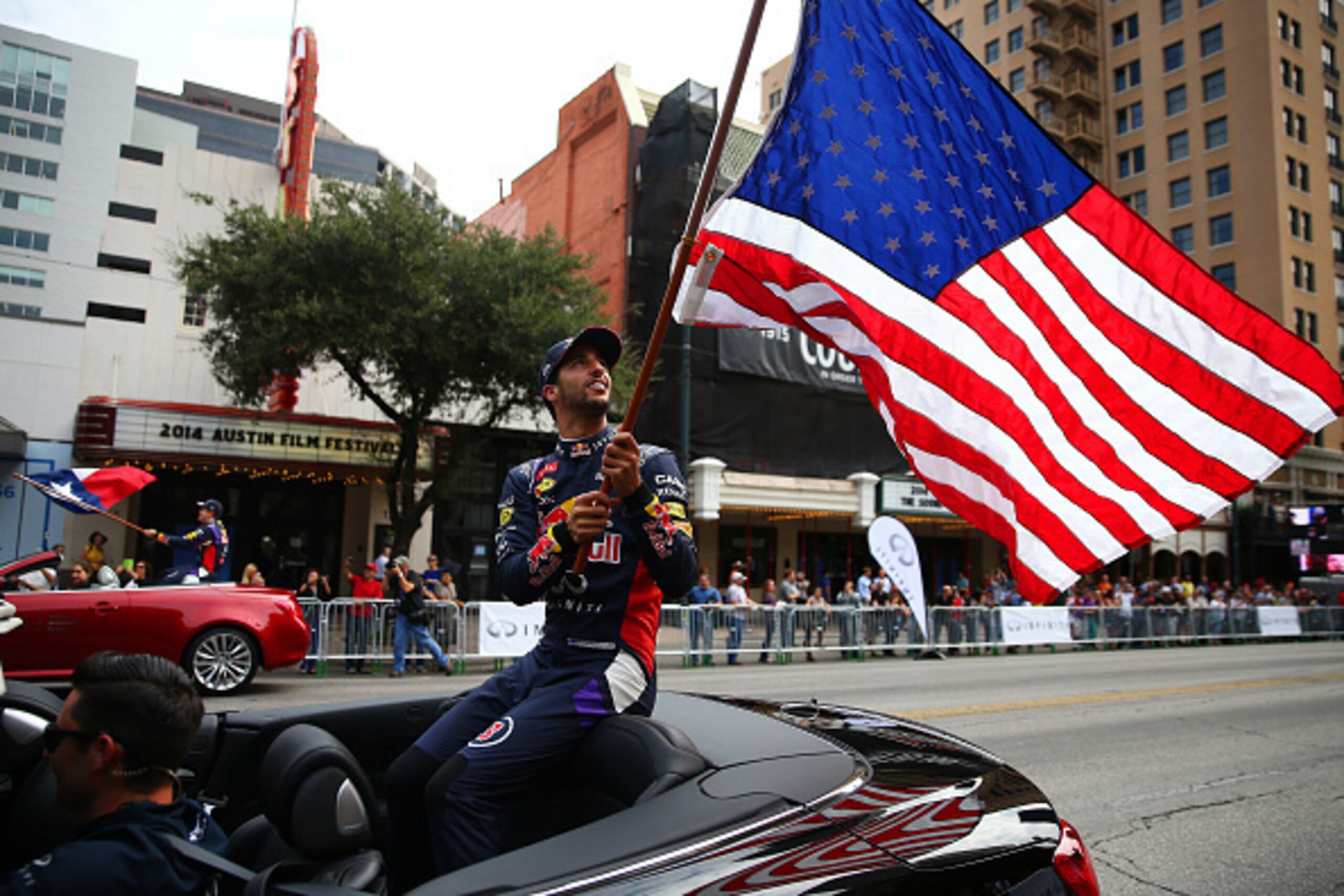 AUSTIN, TX - OCTOBER 29:  Daniel Ricciardo of Australia and Infiniti Red Bull Racing waves an American national flag along North Congress Avenue backdropped by the Texas Capitol building during previews ahead of the United States Formula One Grand Prix on