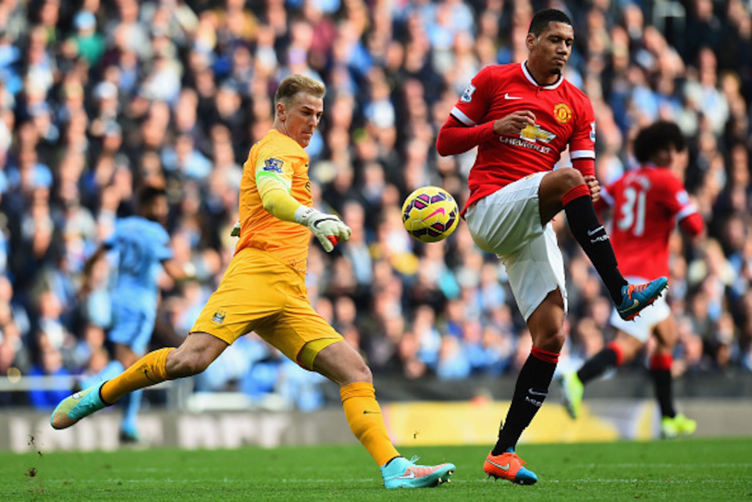 MANCHESTER, ENGLAND - NOVEMBER 02:  Chris Smalling of Manchester United challenges Joe Hart of Manchester City as he clears the ball during the Barclays Premier League match between Manchester City and Manchester United at Etihad Stadium on November 2, 20