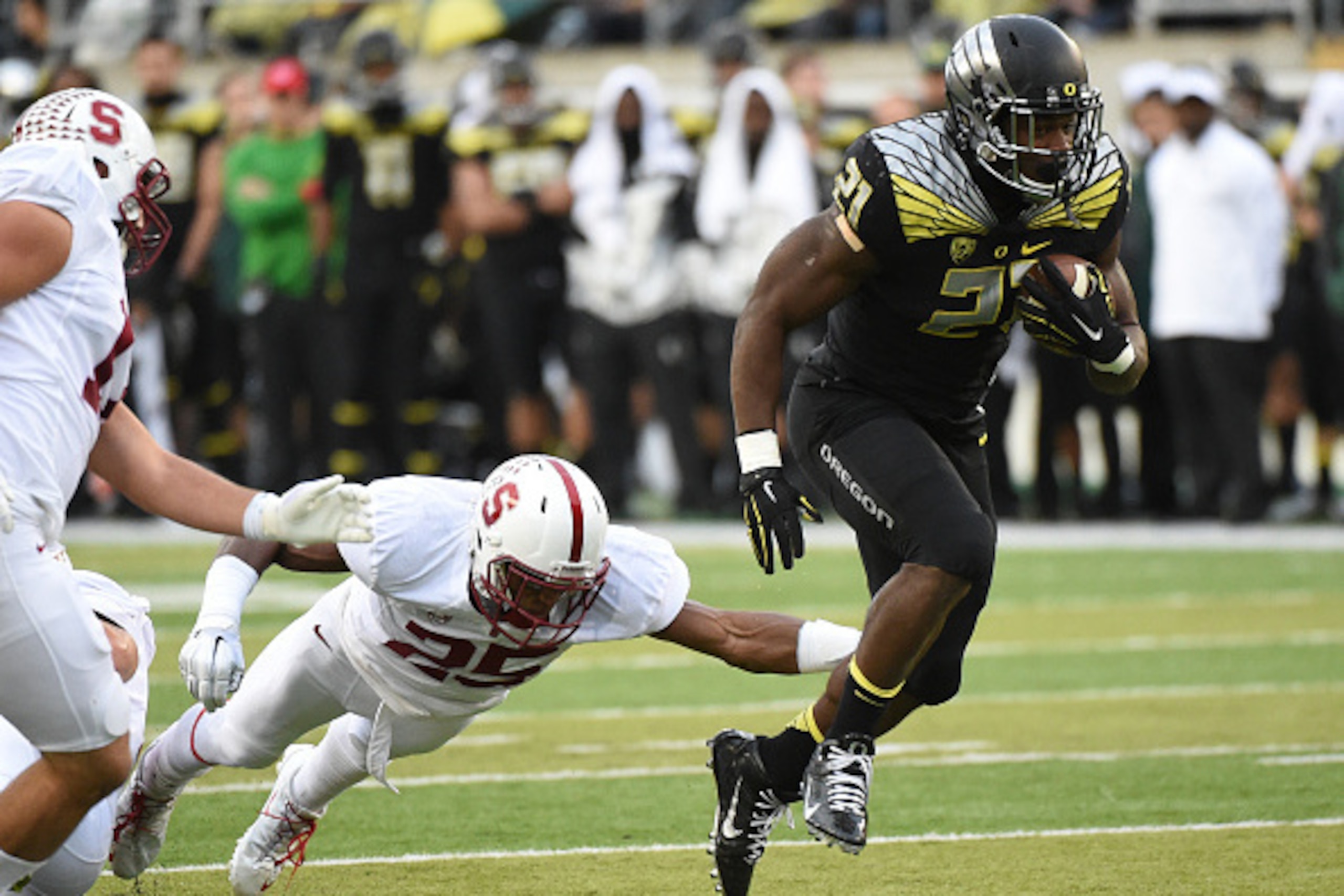 EUGENE, OR - NOVEMBER 1: Cornerback Alex Carter #25 of the Stanford Cardinal dives in a vain attempt to tackle running back Royce Freeman #21 of the Oregon Ducks during the second quarter of the game at Autzen Stadium on November 1, 2014 in Eugene, Oregon