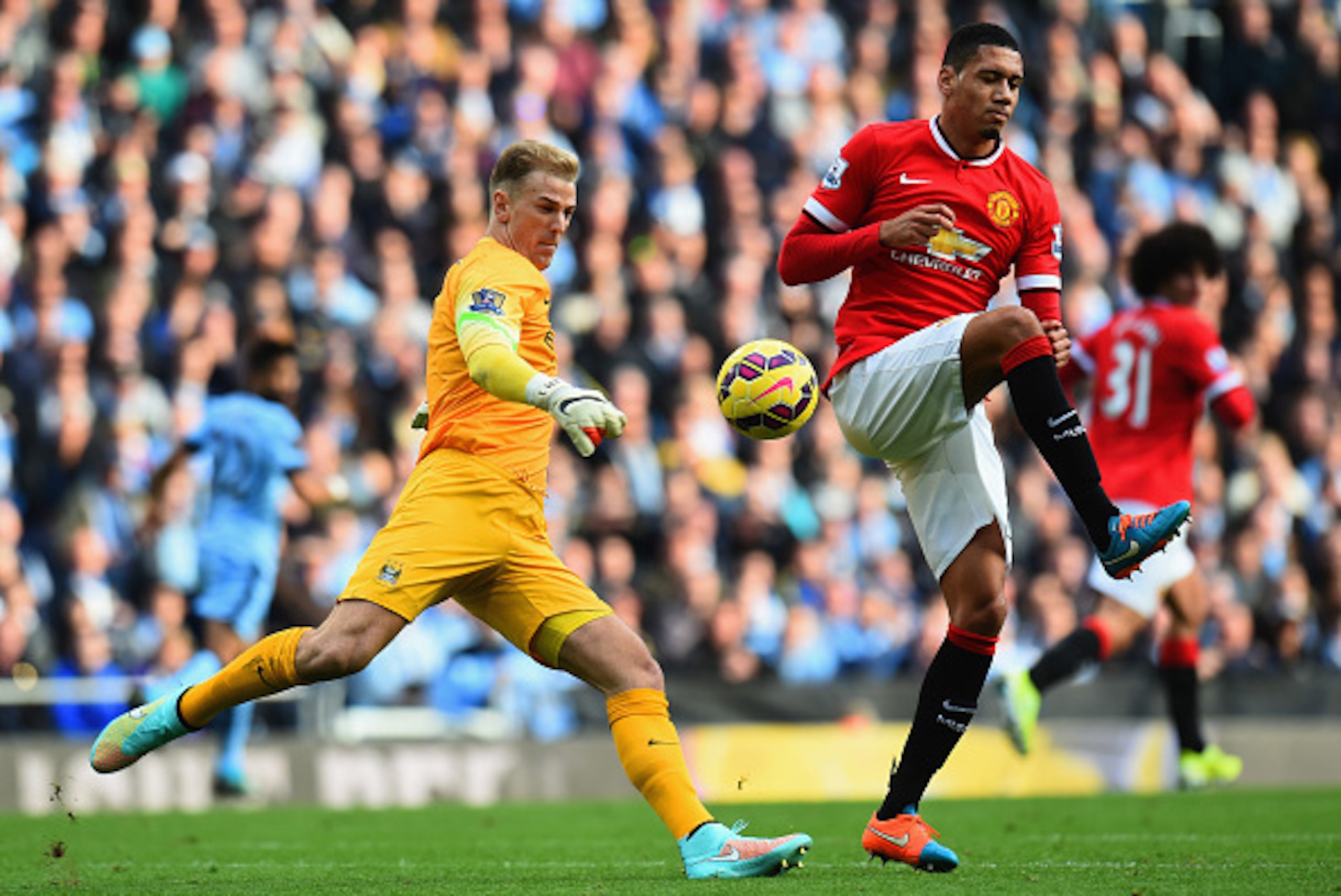 MANCHESTER, ENGLAND - NOVEMBER 02:  Chris Smalling of Manchester United challenges Joe Hart of Manchester City as he clears the ball during the Barclays Premier League match between Manchester City and Manchester United at Etihad Stadium on November 2, 20