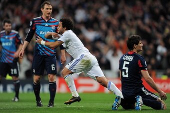 MADRID, SPAIN - MARCH 16:  Marcelo (L) of Real Madrid celebrates scoring his side opening goal past Dejan Lovren of Lyon during the UEFA Champions League round of 16 second leg match between Real Madrid and Lyon at Estadio Santiago Bernabeu on March 16, 2