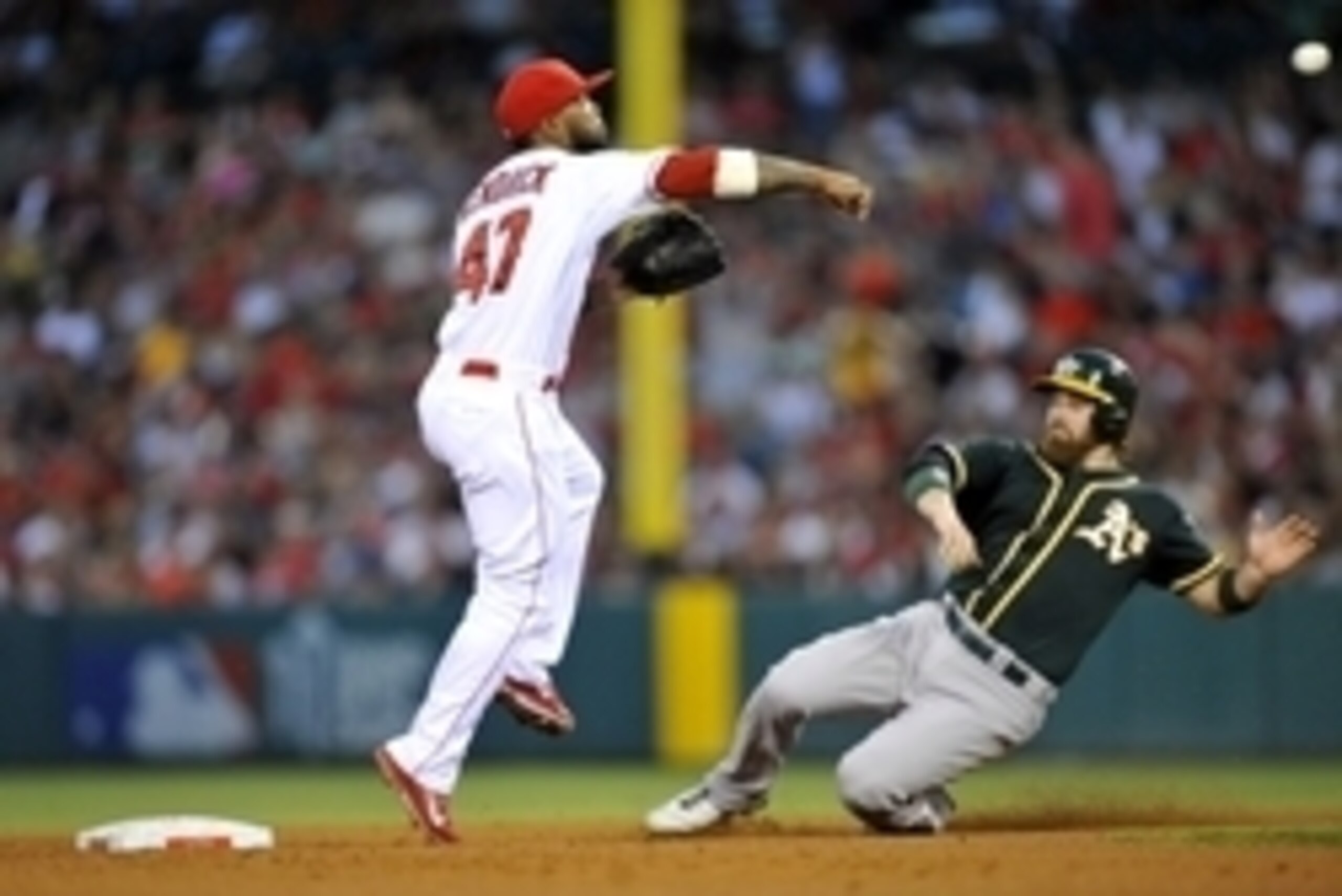August 30, 2014; Anaheim, CA, USA; Los Angeles Angels second baseman Howie Kendrick (47) throws to first as  Oakland Athletics catcher Derek Norris (36) slides into second in the fourth inning at Angel Stadium of Anaheim. Mandatory Credit: Gary A. Vasquez