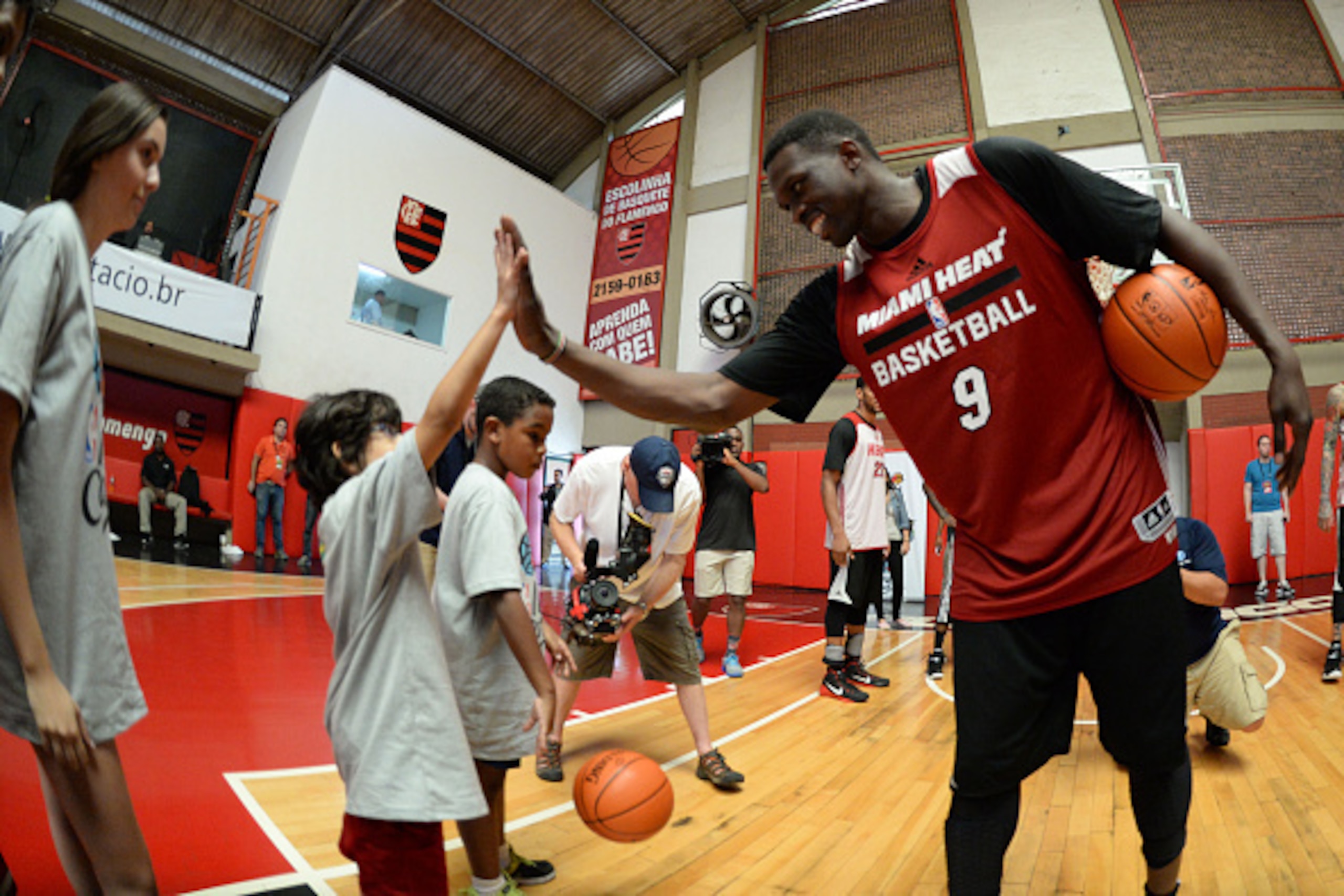 RIO DE JANEIRO, BRAZIL - OCTOBER 9: Luol Deng #9 of the Miami Heat and a participant high five during an NBA Cares clinic at Flamengo Club Borges de Medeiros as a part of NBA Global Games on October 9, 2014 in Rio de Janeiro, Brazil.  NOTE TO USER:  User 