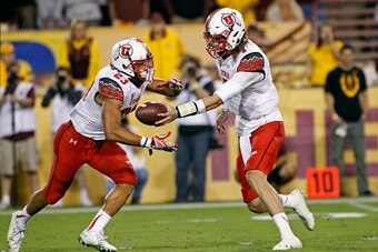 TEMPE, AZ - NOVEMBER 01:  Quarterback Travis Wilson #7 of the Utah Utes (R) hands the ball off to running back Devontae Booker #23 during the fourth quarter of a college football game against the Arizona State Sun Devils at Sun Devil Stadium on November 1