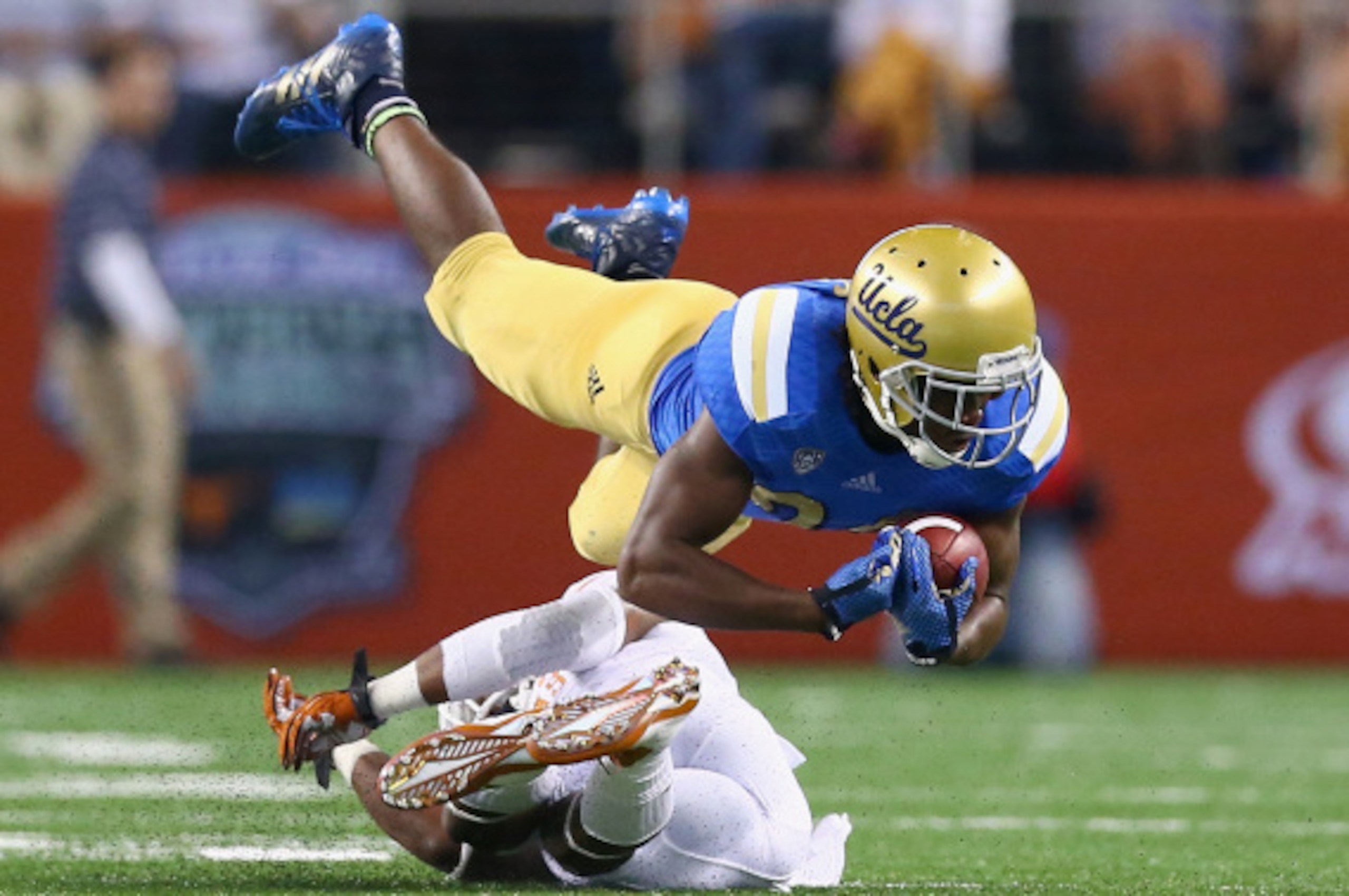 ARLINGTON, TX - SEPTEMBER 13:  Paul Perkins #24 of the UCLA Bruins is tackled by Quandre Diggs #6 of the Texas Longhorns in the first quarter at AT&T Stadium on September 13, 2014 in Arlington, Texas.  (Photo by Ronald Martinez/Getty Images)