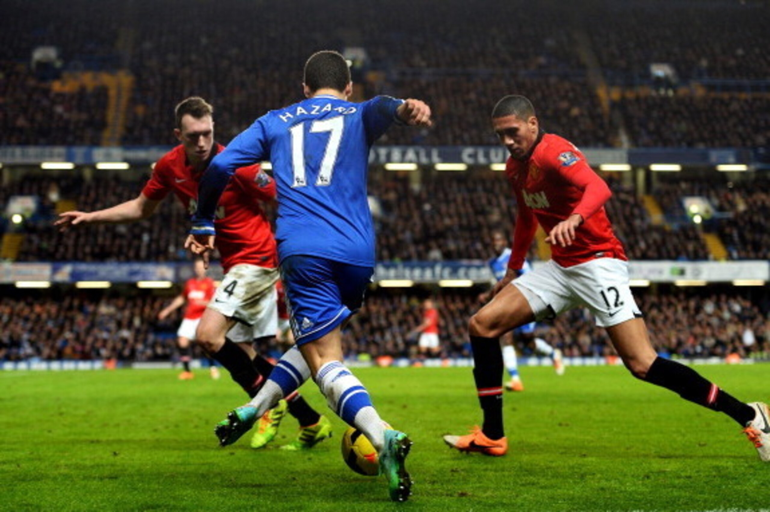 LONDON, ENGLAND - JANUARY 19:  Eden Hazard of Chelsea is challenged by Phil Jones (L) and Chris Smalling (R) of Manchester United during the Barclays Premier League match between Chelsea and Manchester United at Stamford Bridge on January 19, 2014 in Lond
