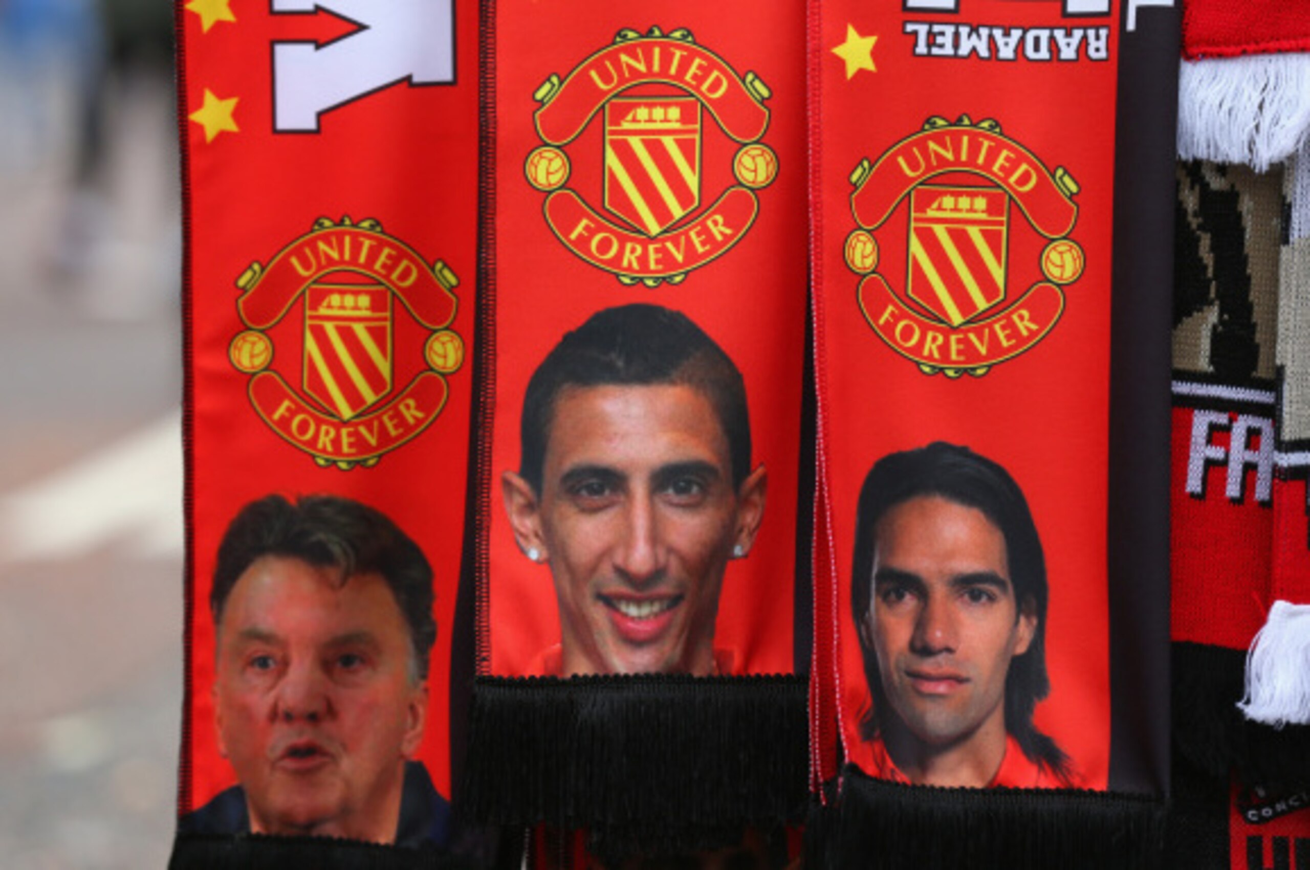 MANCHESTER, ENGLAND - SEPTEMBER 14:  A vendor sells scarves showing  Manager Louis van Gaal and new signings Falcao and Angel Di Maria prior to the Barclays Premier League match between Manchester United and Queens Park Rangers at Old Trafford on Septembe