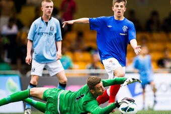HONG KONG - MAY 26:  Angus Gunn (bottom) of Manchester City stops a shot from Charlie Telfer of Rangers on day three of the Hong Kong International Soccer Sevens at Hong Kong Football Club on May 26, 2013 in Hong Kong, Hong Kong.  (Photo by Victor Fraile/