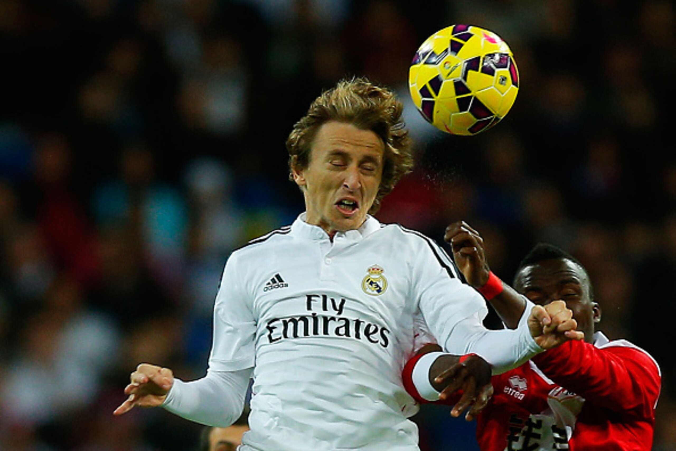 MADRID, SPAIN - NOVEMBER 08: Luka Modric of Real Madrid CF wins the header after Mohammed Fatau of Rayo Vallecano de Madrid during the La Liga match between Real Madrid CF and Rayo Vallecano de Madrid at Estadio Santiago Bernabeu on November 8, 2014 in Ma