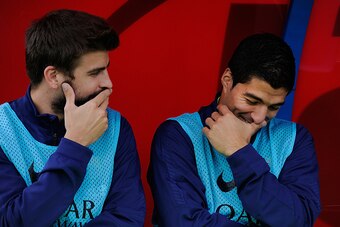 ALMERIA, SPAIN - NOVEMBER 08: Gerard Pique of FC Barcelona chats with team-mate Luis Suarez on the substitutes bench during the La Liga match between UD Almeria and FC Barcelona at estadio de los Juegos Mediterraneos on November 8, 2014 in Almeria, Spain.